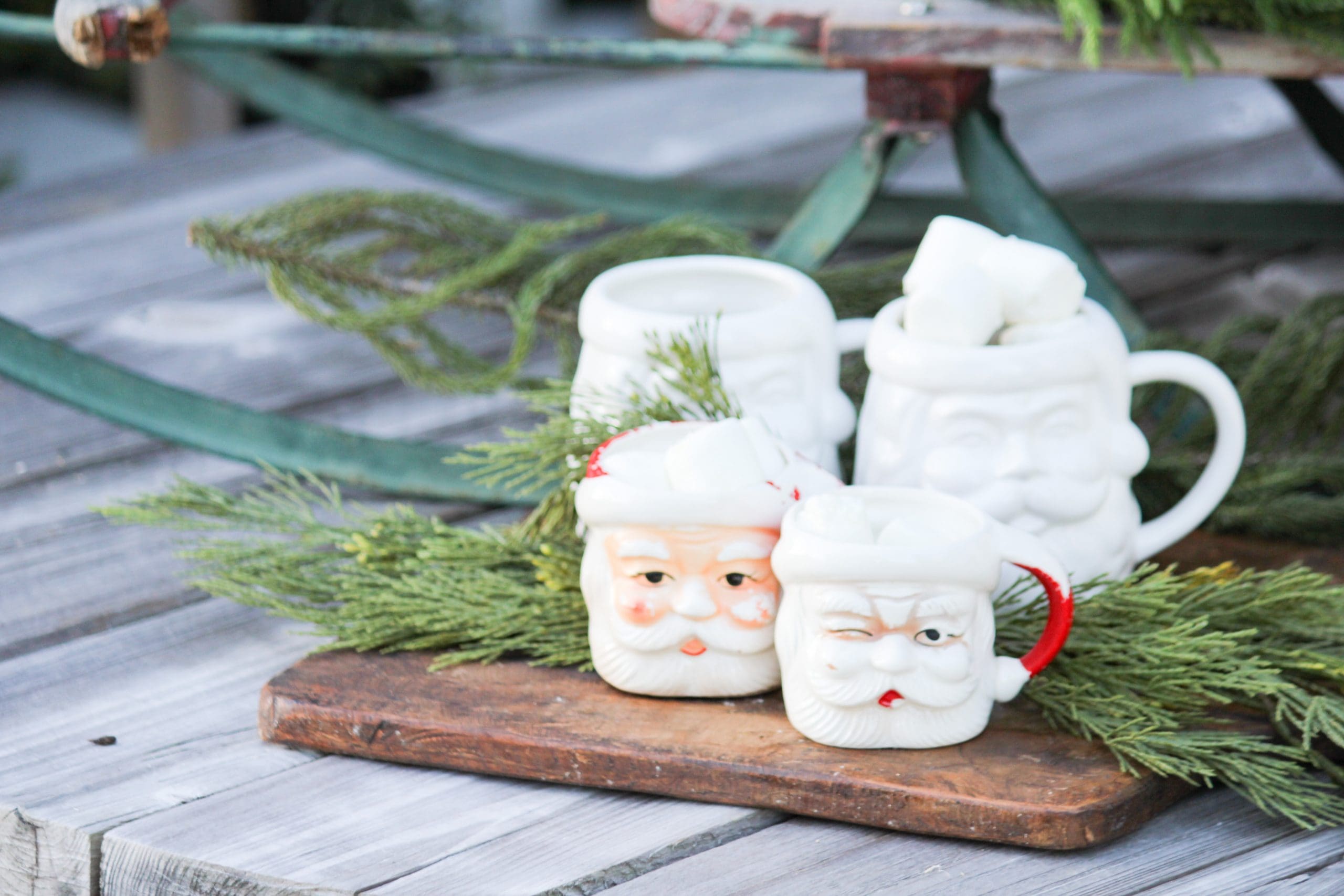 close up of vintage Santa mugs styled on an outdoor coffee table