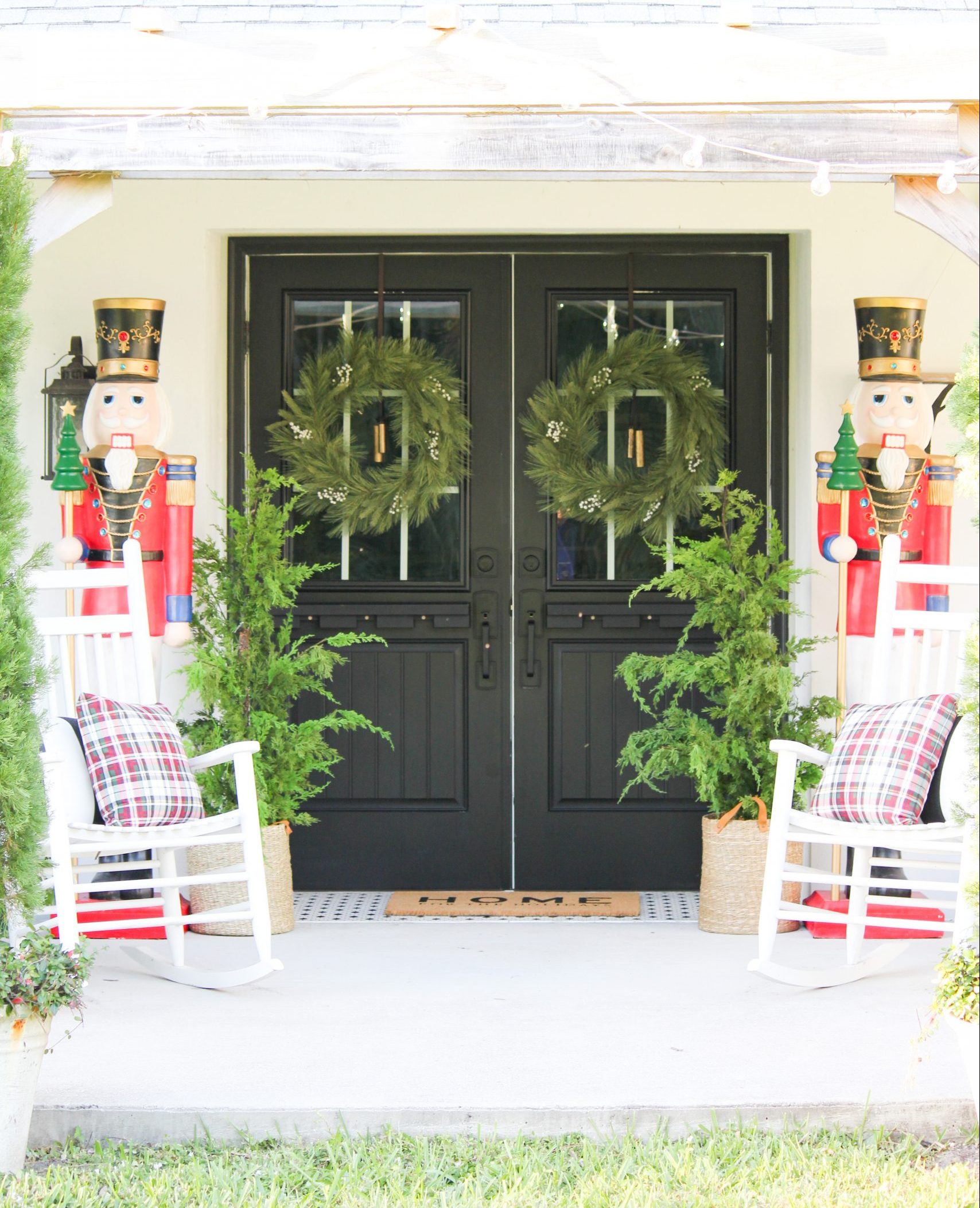 view of front doors with wreaths and bright colored nutcrackers