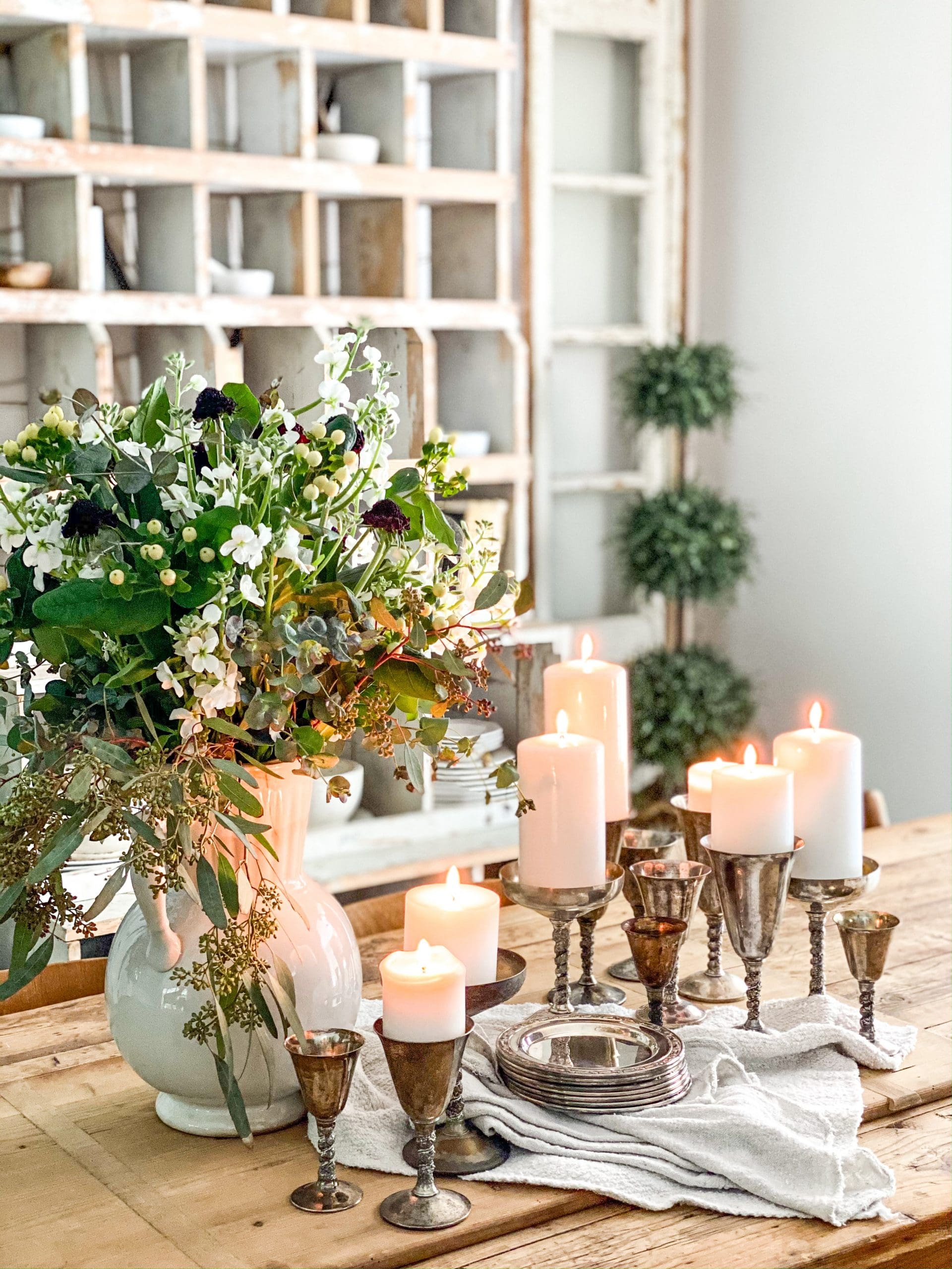 beautiful flower arrangement in an ironstone pitcher and different sizes of candles on smaller gold candlesticks