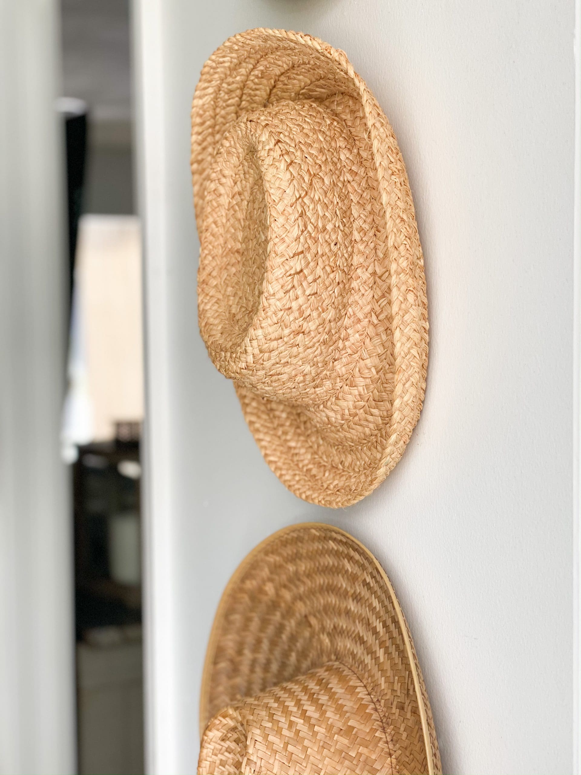 old straw hats hanging on entryway wall