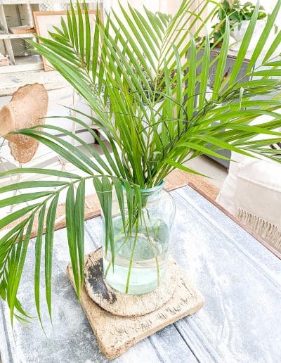 Vintage pedestal with green glass vase & freshly trimmed arrica palm fronds.