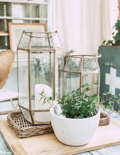 Zinc-topped coffee table, decorated with old bread board, wicker basket & bronze/glass lanterns. A large white mortar & pestle completes the vignette.