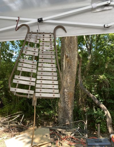 Antique metal lyre hanging from an outdoor white tent frame.