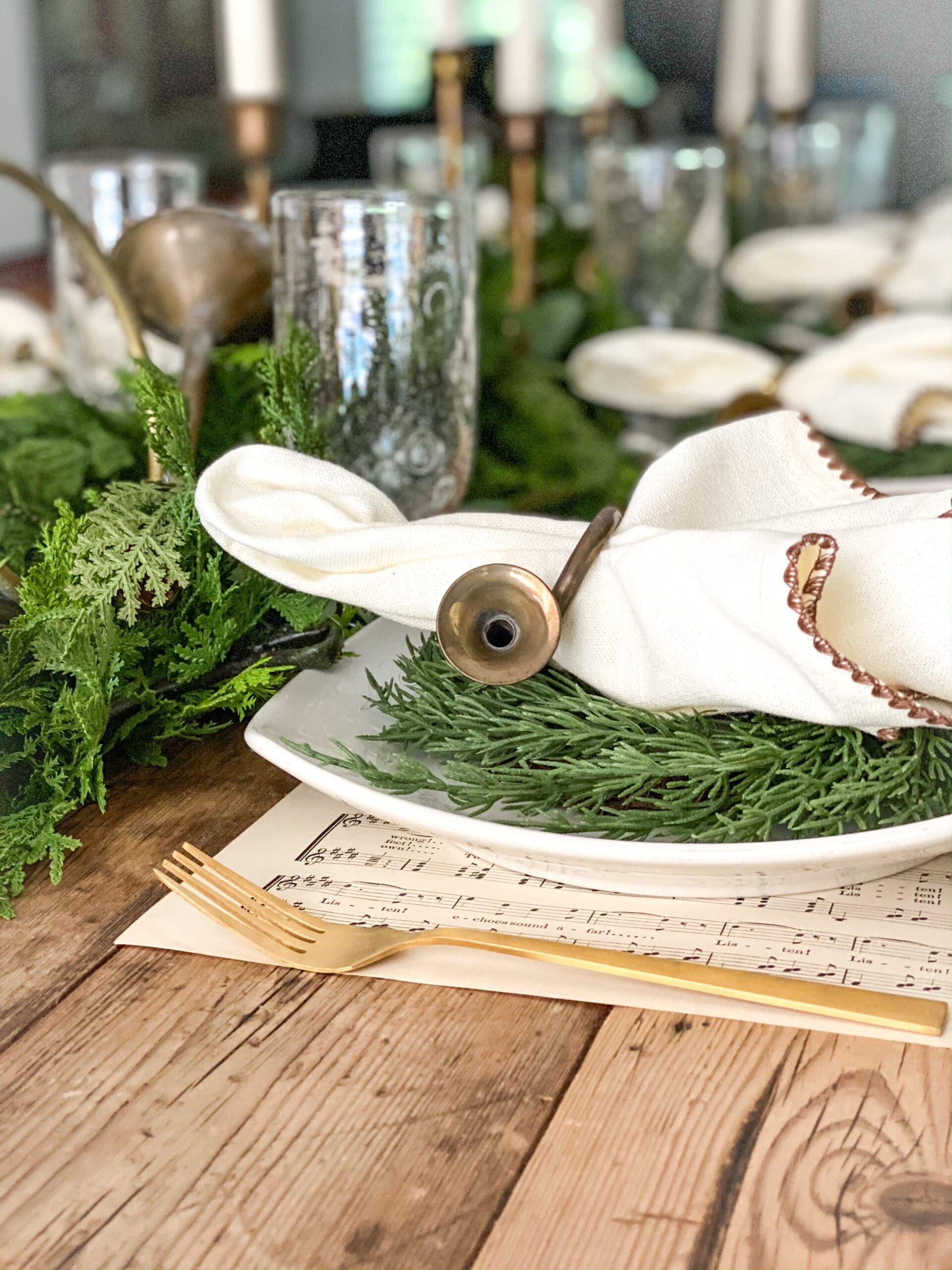 close up of a place setting with small wreaths, gold flatware, and a piece of sheet music as a placemat
