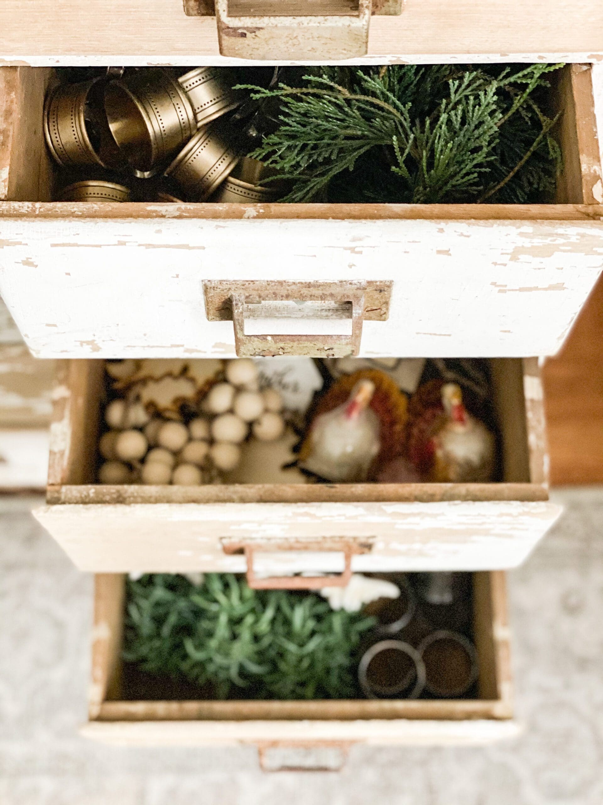 drawers in a white apothecary holding different kinds of different Christmas napkin rings