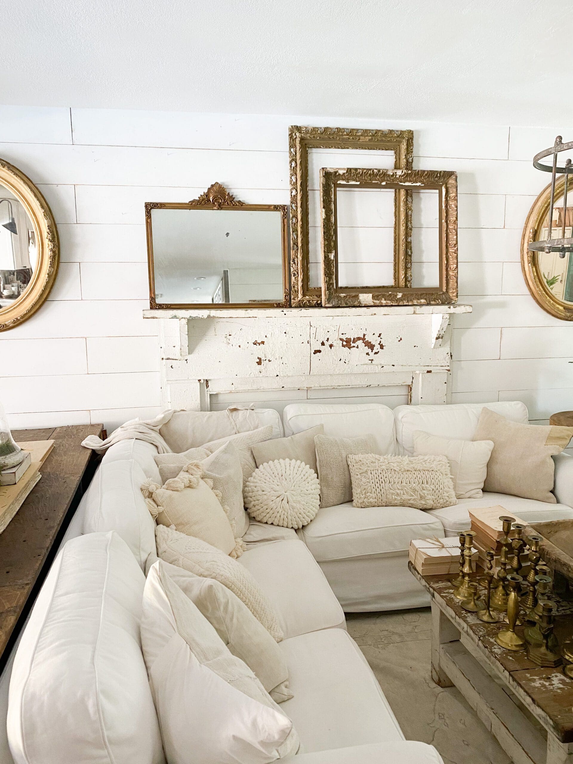 white mantel with a large gold mirror and two wooden frames beside the mirror