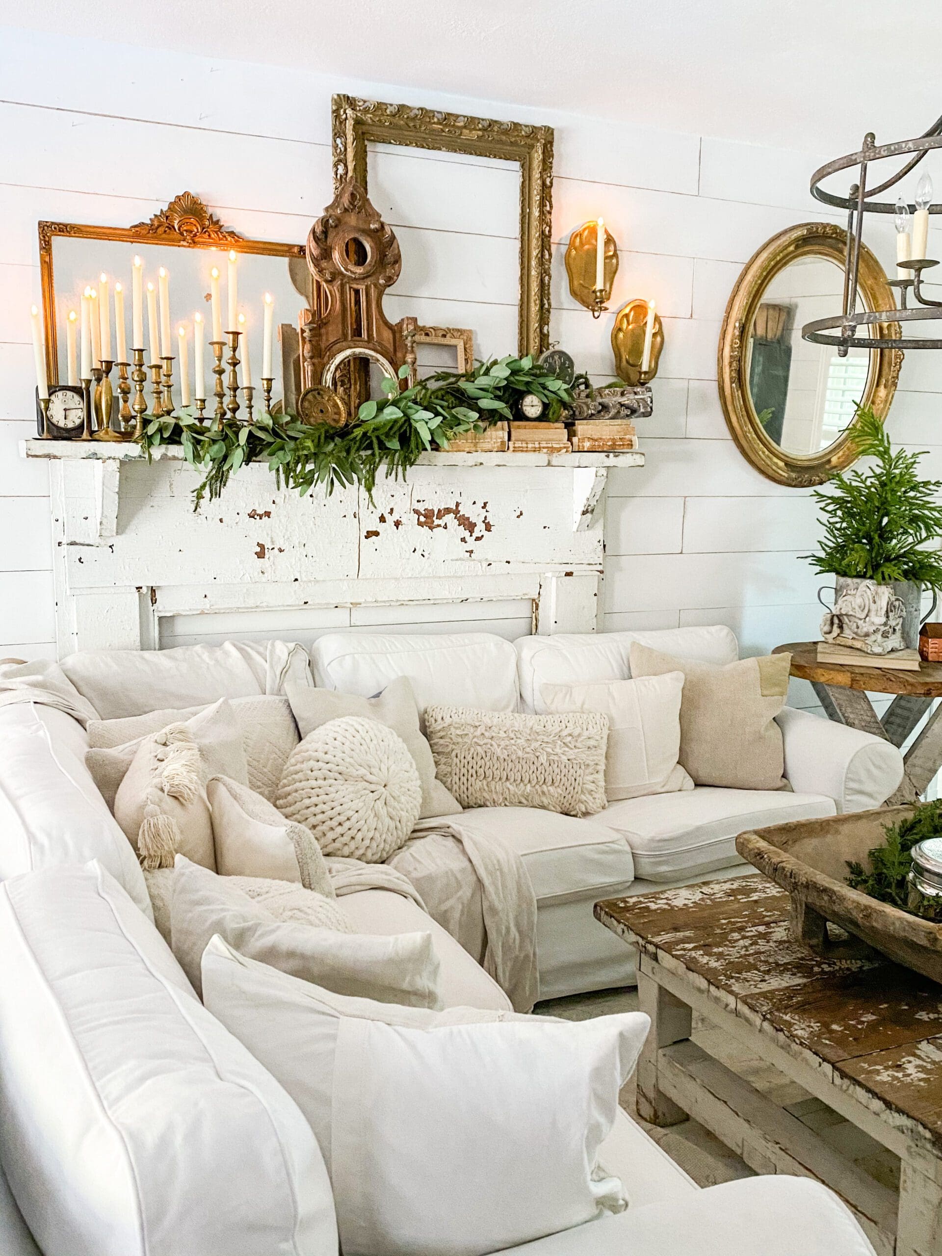 wide angle of a cozy white couch in front of a white wooden mantel styled for winter