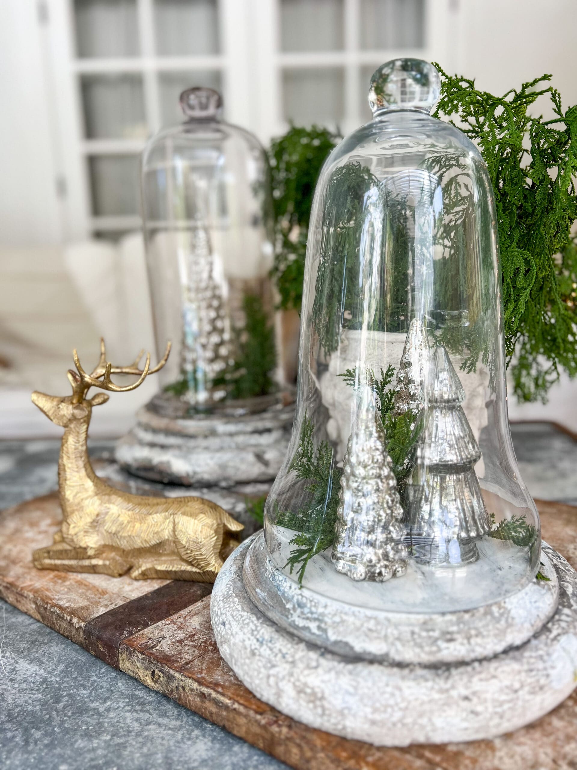 cloches with mercury glass trees underneath next to a brass deer