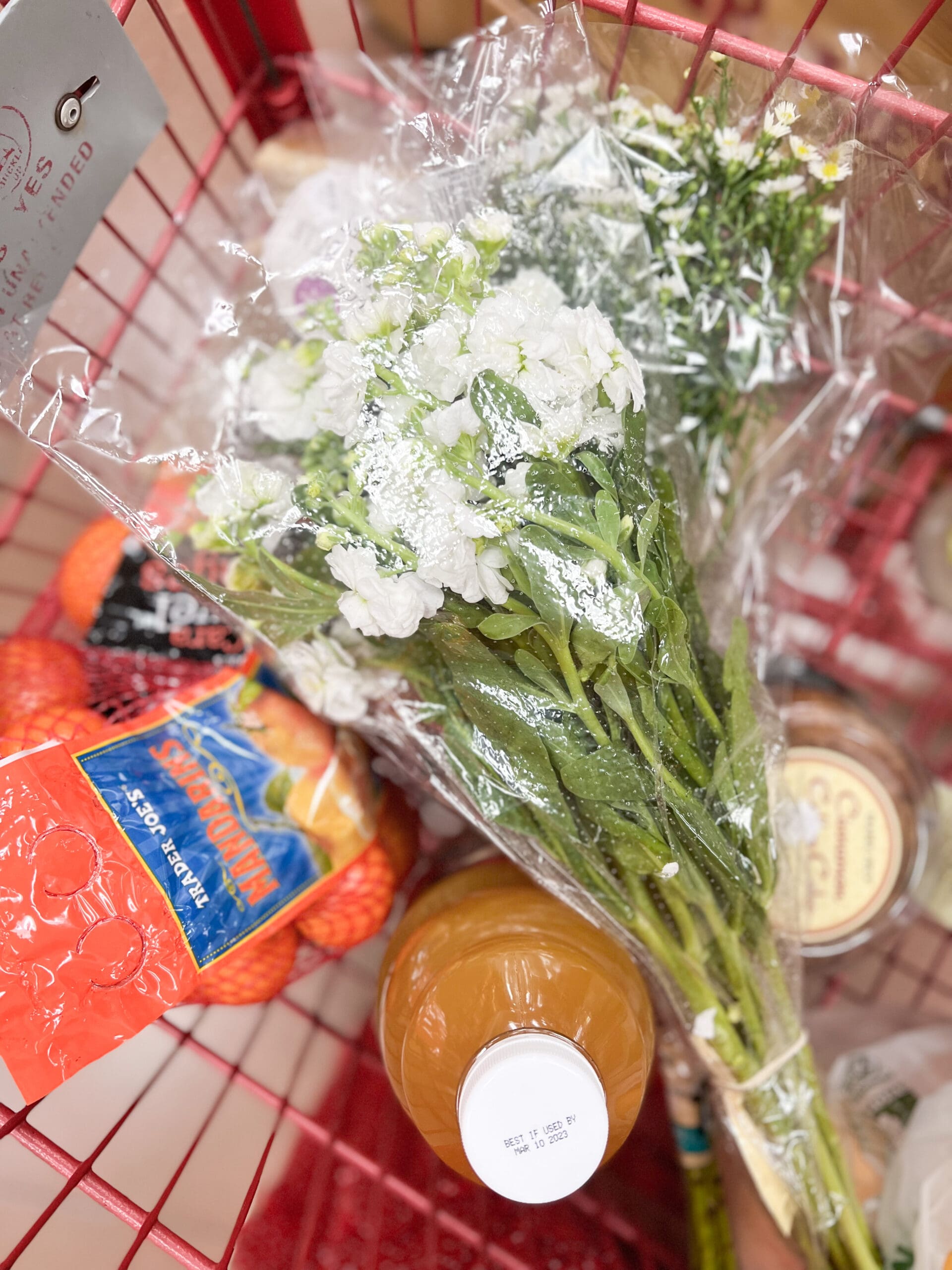 oranges, cider, and fresh white flowers in a shopping cart along with other materials