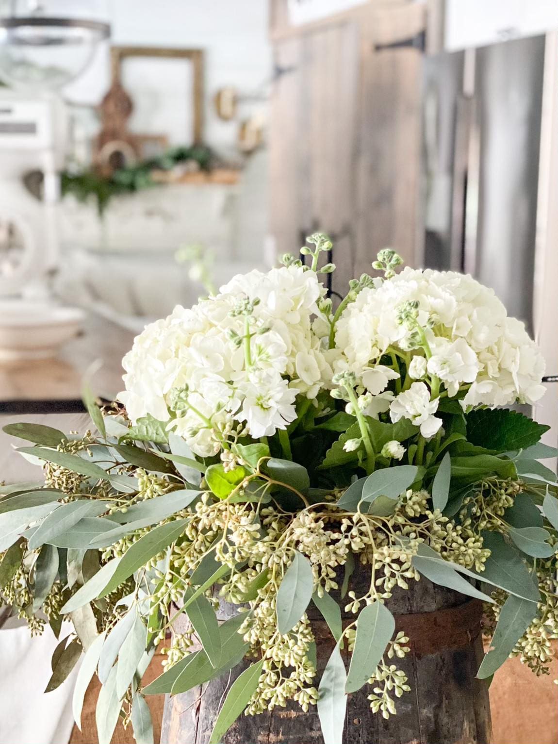 beautiful fresh white flowers arranged with fresh greenery in a cute pitcher