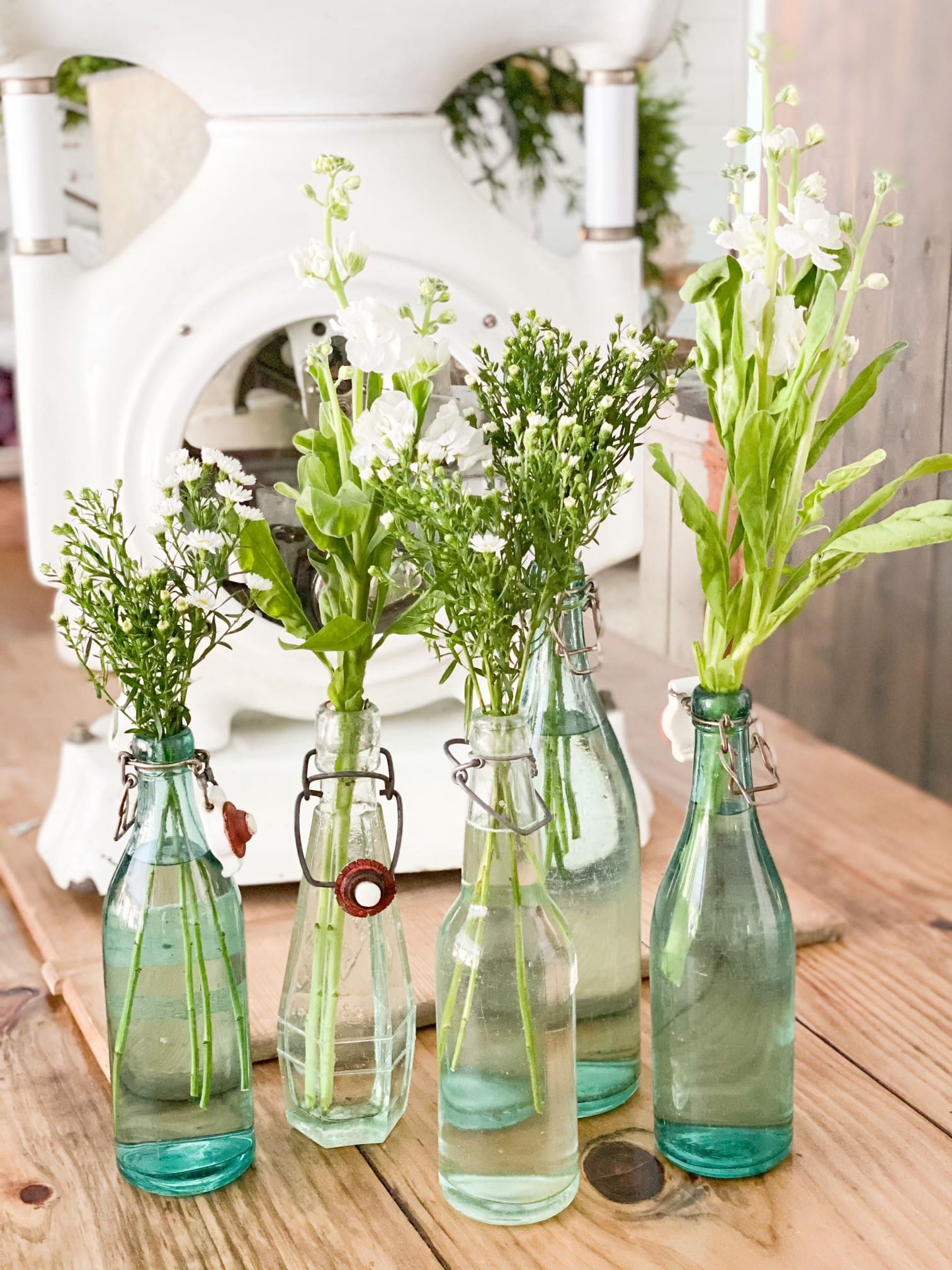 small bouquets of small white flowers arranged in vintage glass bottles