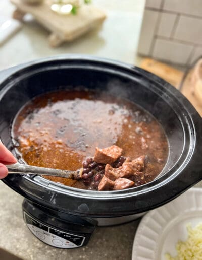 Stirring the beef tips & black beans in the crockpot with hot steam coming off.