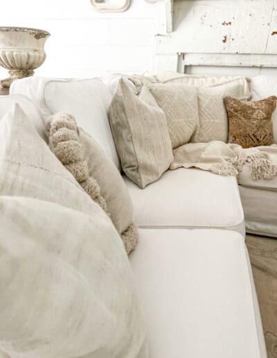 Comfy white couch with assorted white cushions and throw