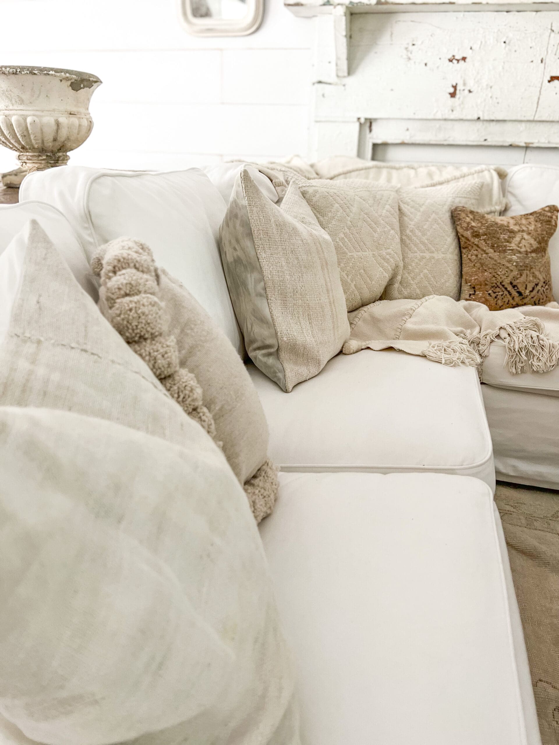 Comfy white couch with assorted white cushions and throw