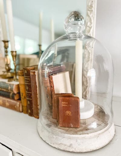 Cloche covering small vintage books & remote controlled white candle