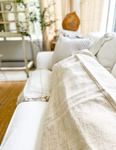 Long, comfy, white linen throw pillow on white couch in back room.
