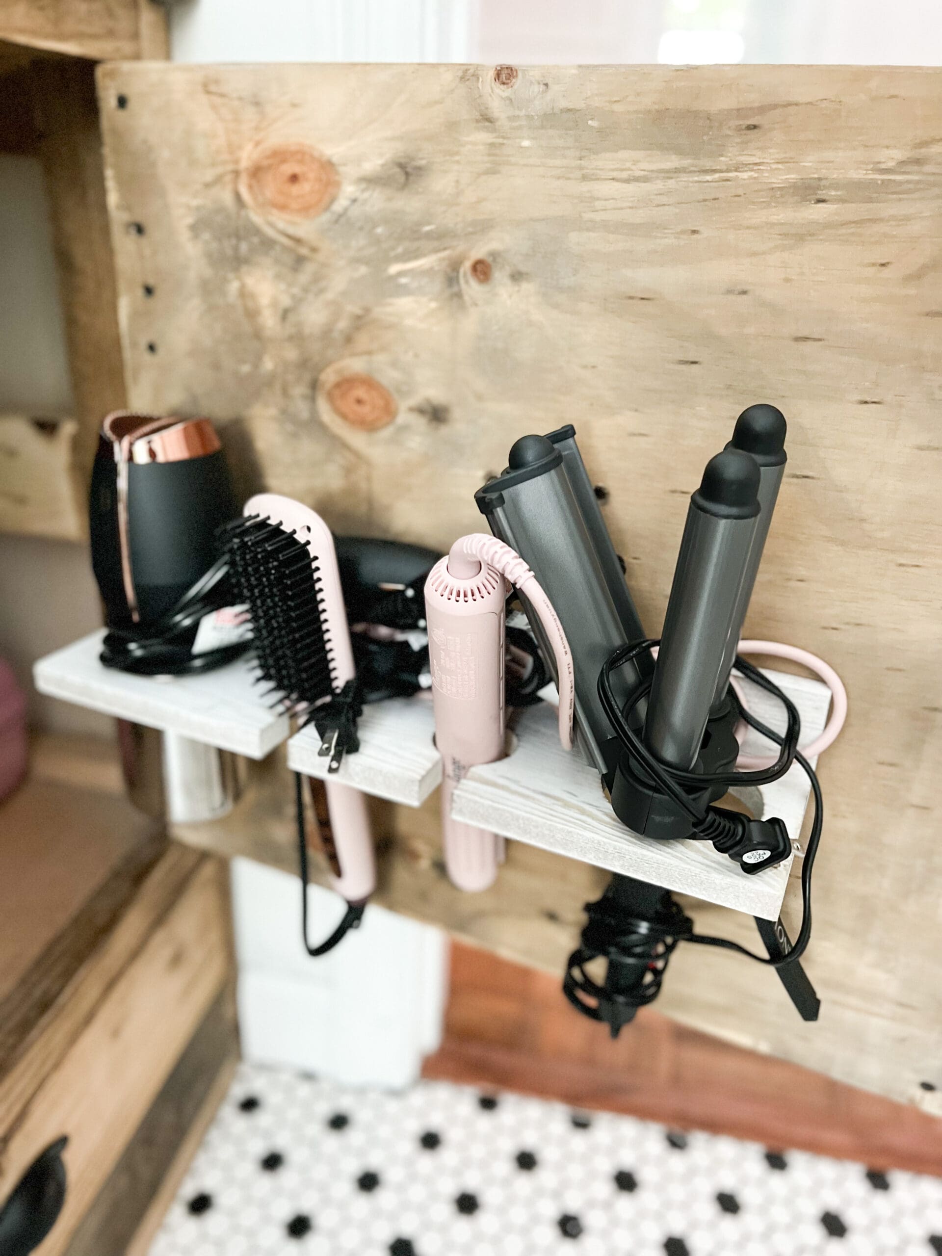 With one cabinet door open, wood organizer is screwed to the backside of the door holding brushes, curlers, & blow dryers out of harm's way.