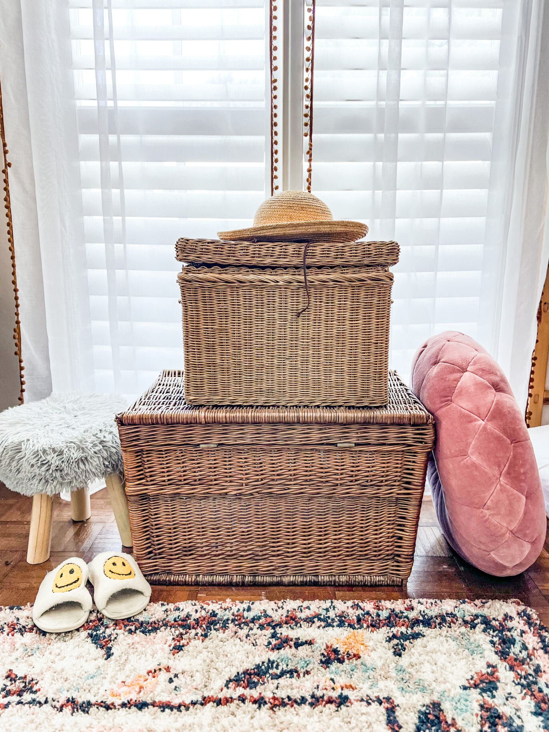 Large baskets stacked on top of each other with smiley face slippers and a large pillow next to it