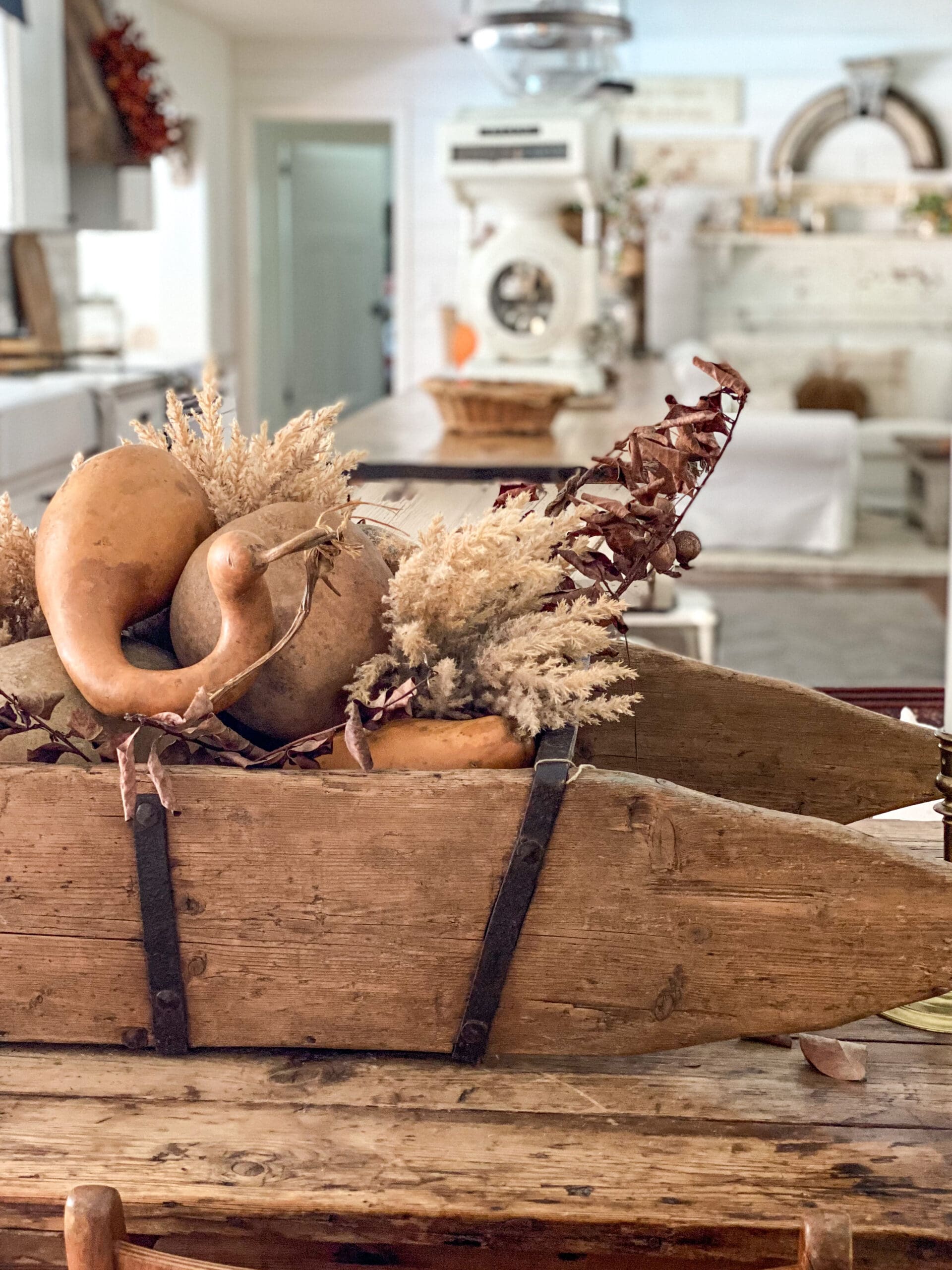 large wooden trough full of gourds, dried leaves, and faux fall stems