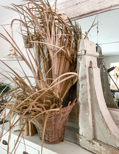 Woven basket with dried palm fronds next to a large tan architectural piece