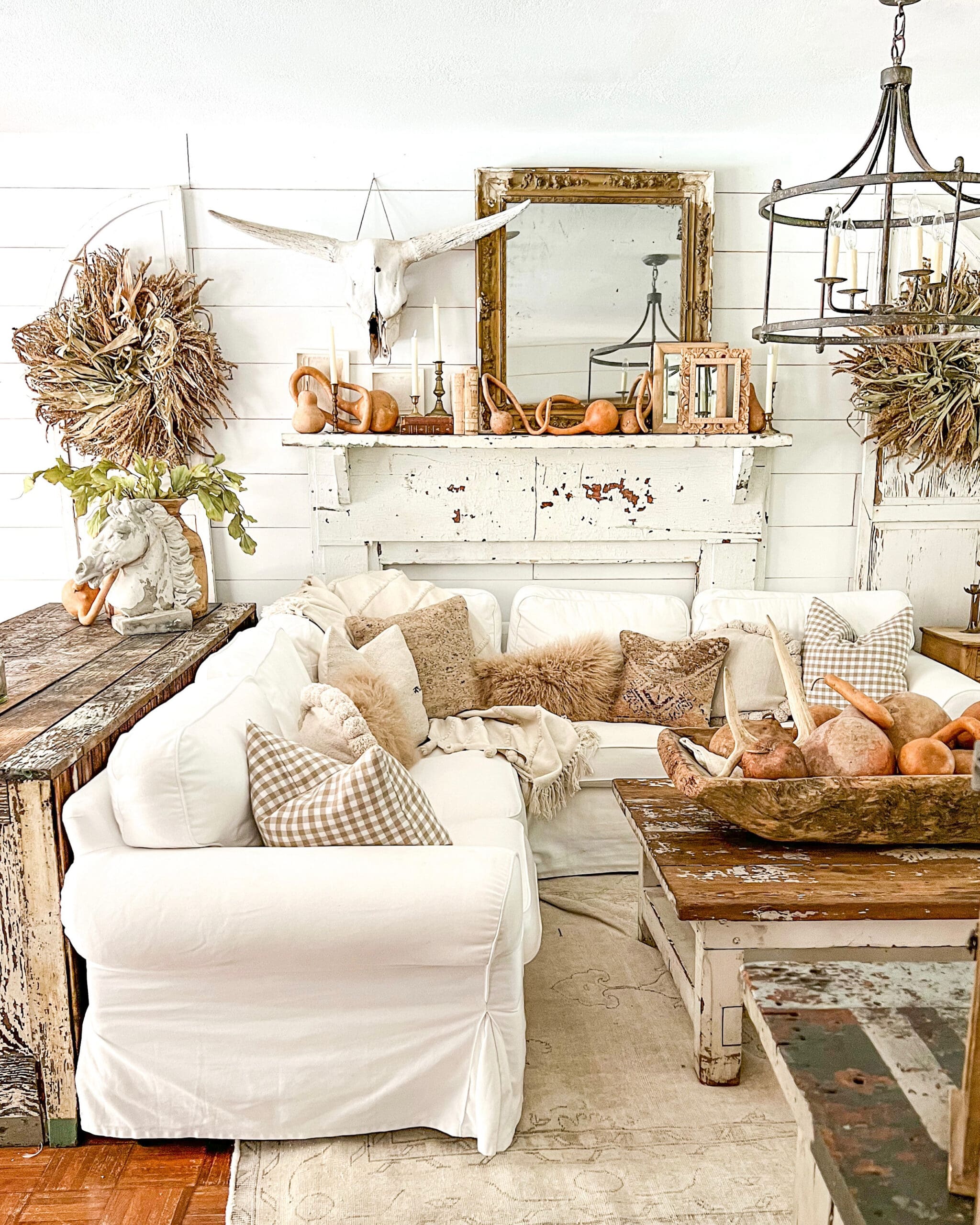 family room styled for fall with gourds, an antique gold mirror, and cozy fall colored pillows