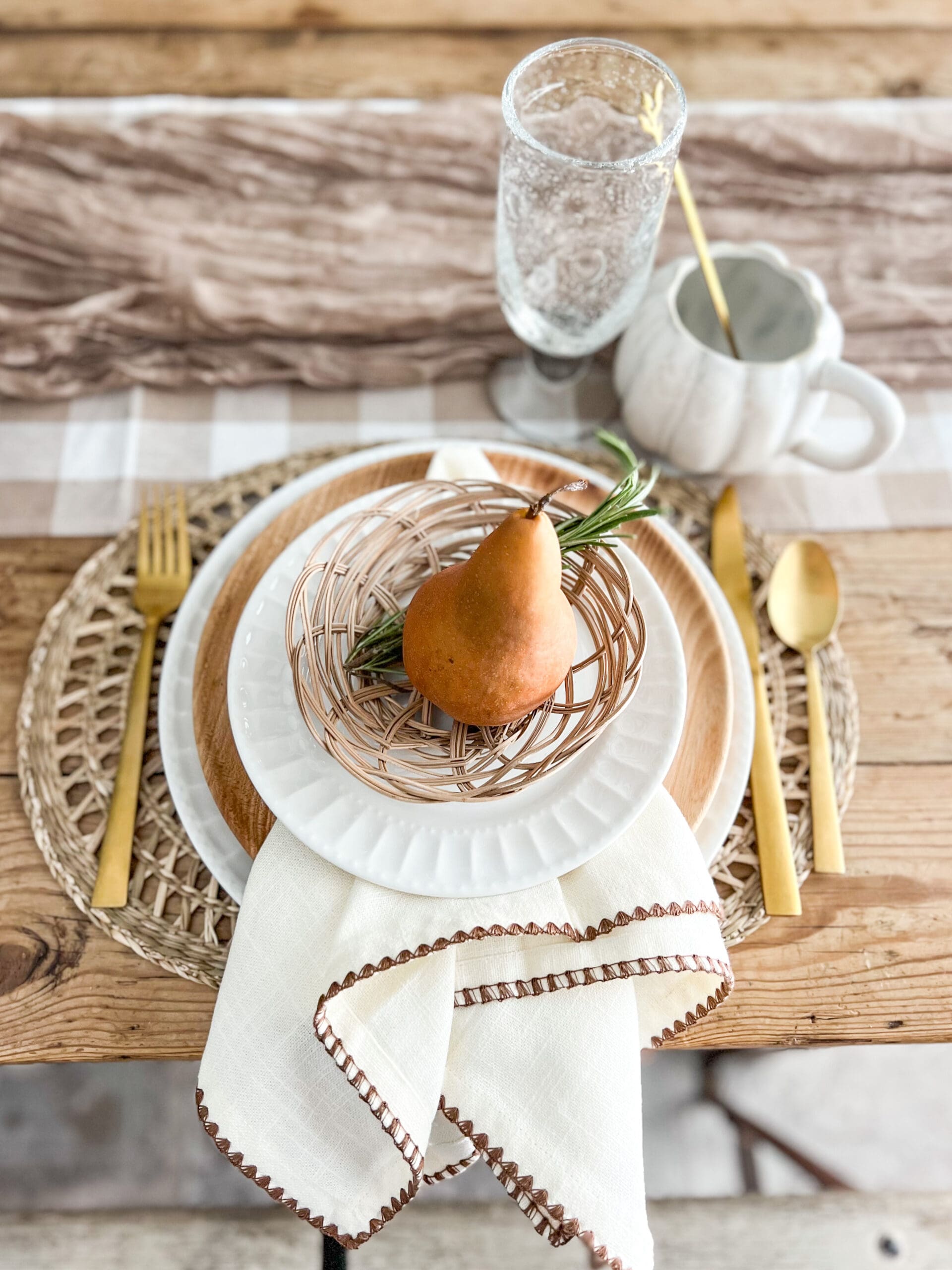 small pear with a rosemary sprig in a small woven basket on white dishes