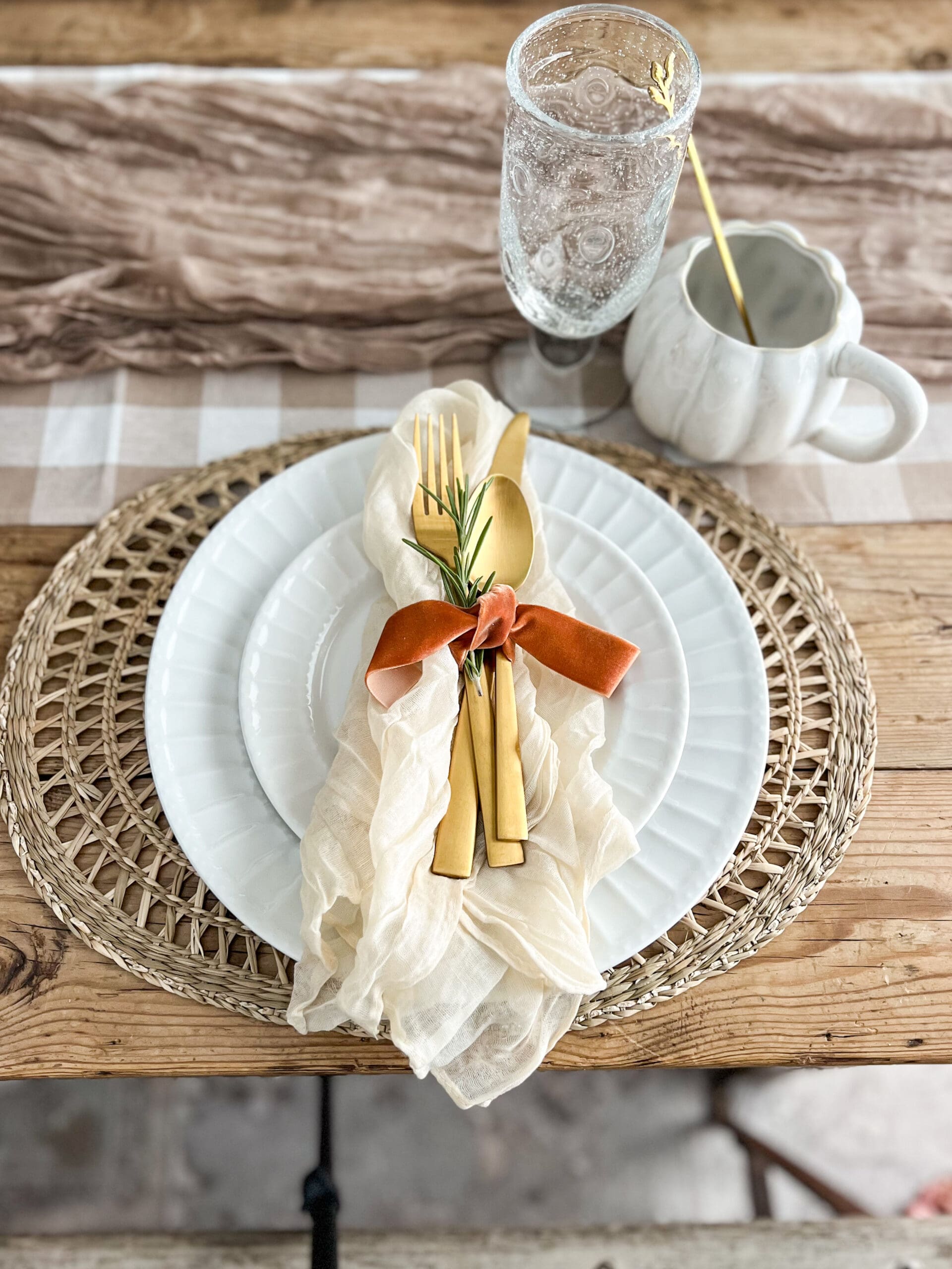 golden flatware tied with ribbon and a sprig of rosemary