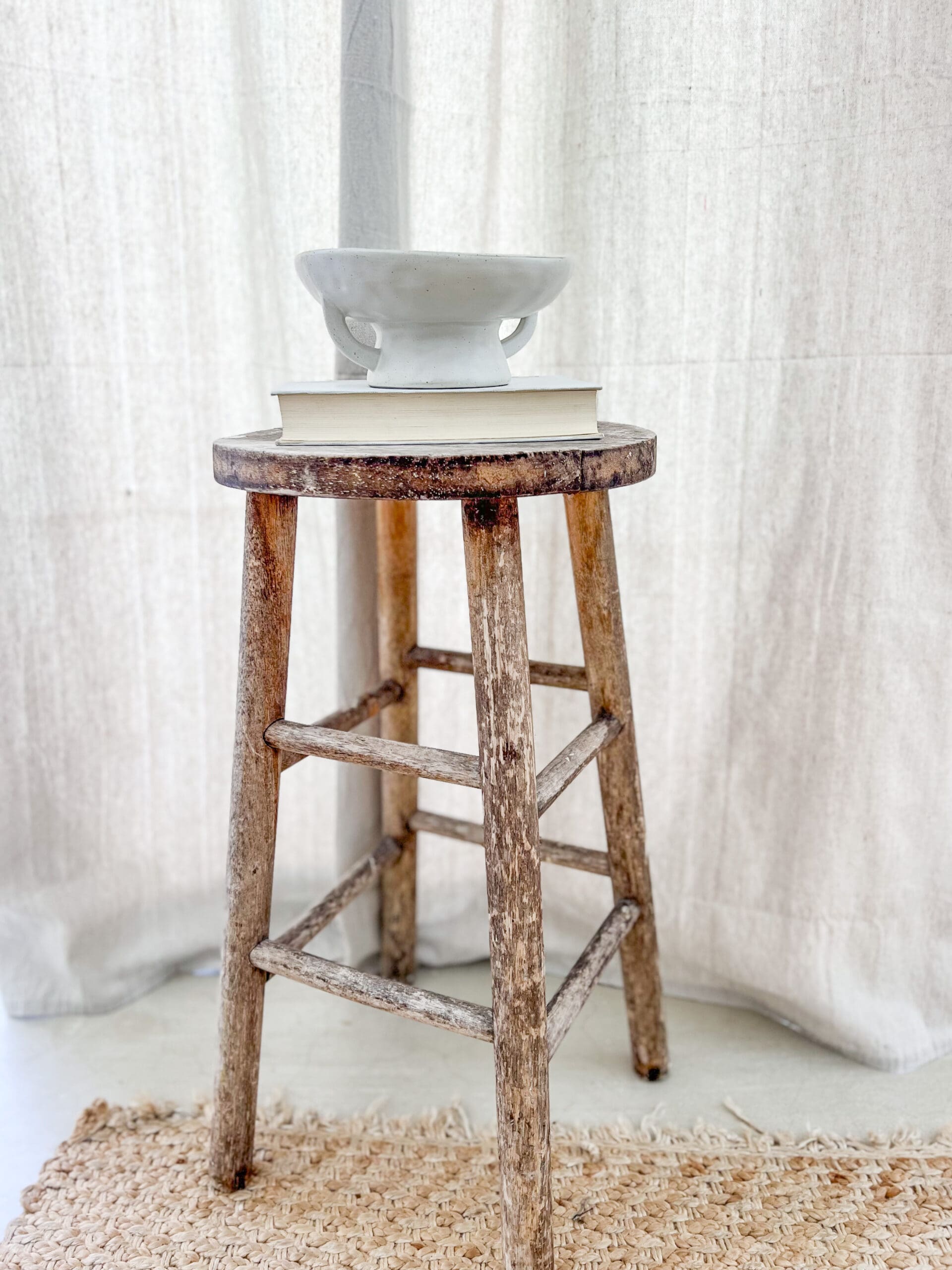 round wooden stool with a vintage white book and ironstone bowl on top
