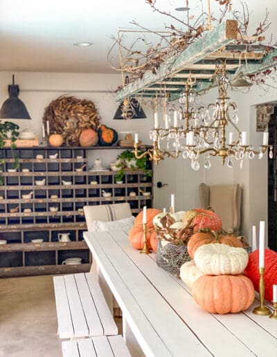 stacked pumpkins of different shapes and sizes stacked along the middle of a long white table with candlesticks