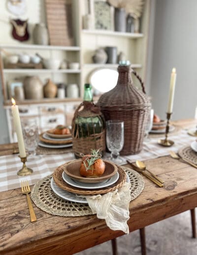 table setting styled with woven chargers, golden flatware and freshly baked rolls