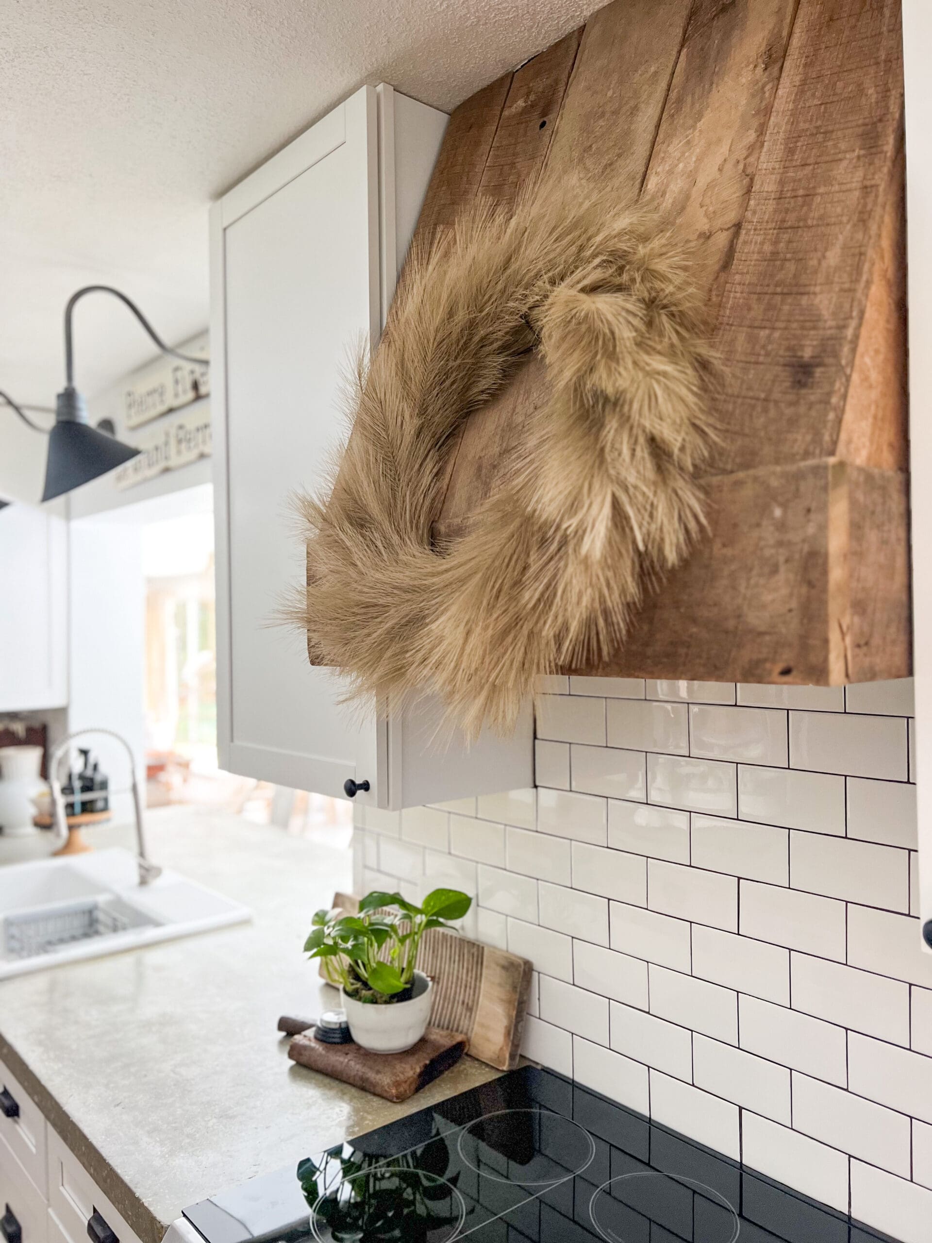 pampas grass wreath hanging on a wooden hood above stove