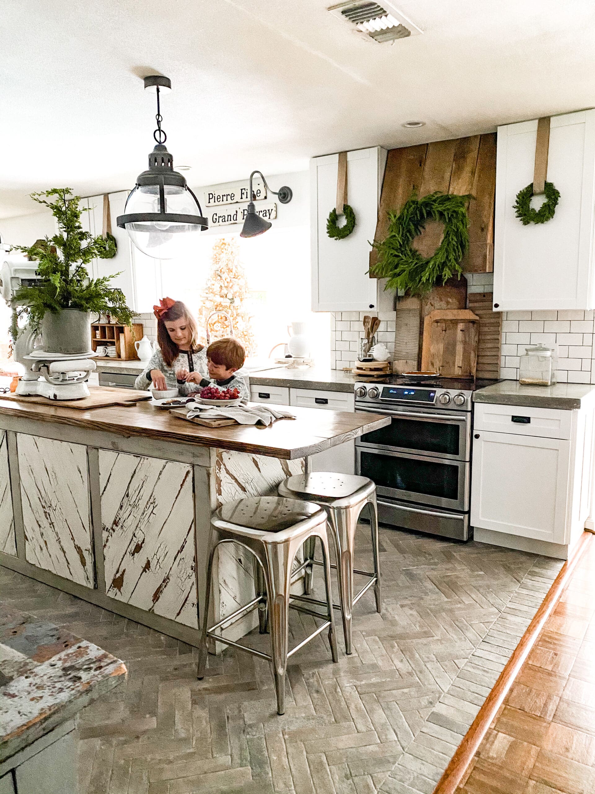 Addy and Harrison baking in the kitchen decorated with Christmas decor and greenery