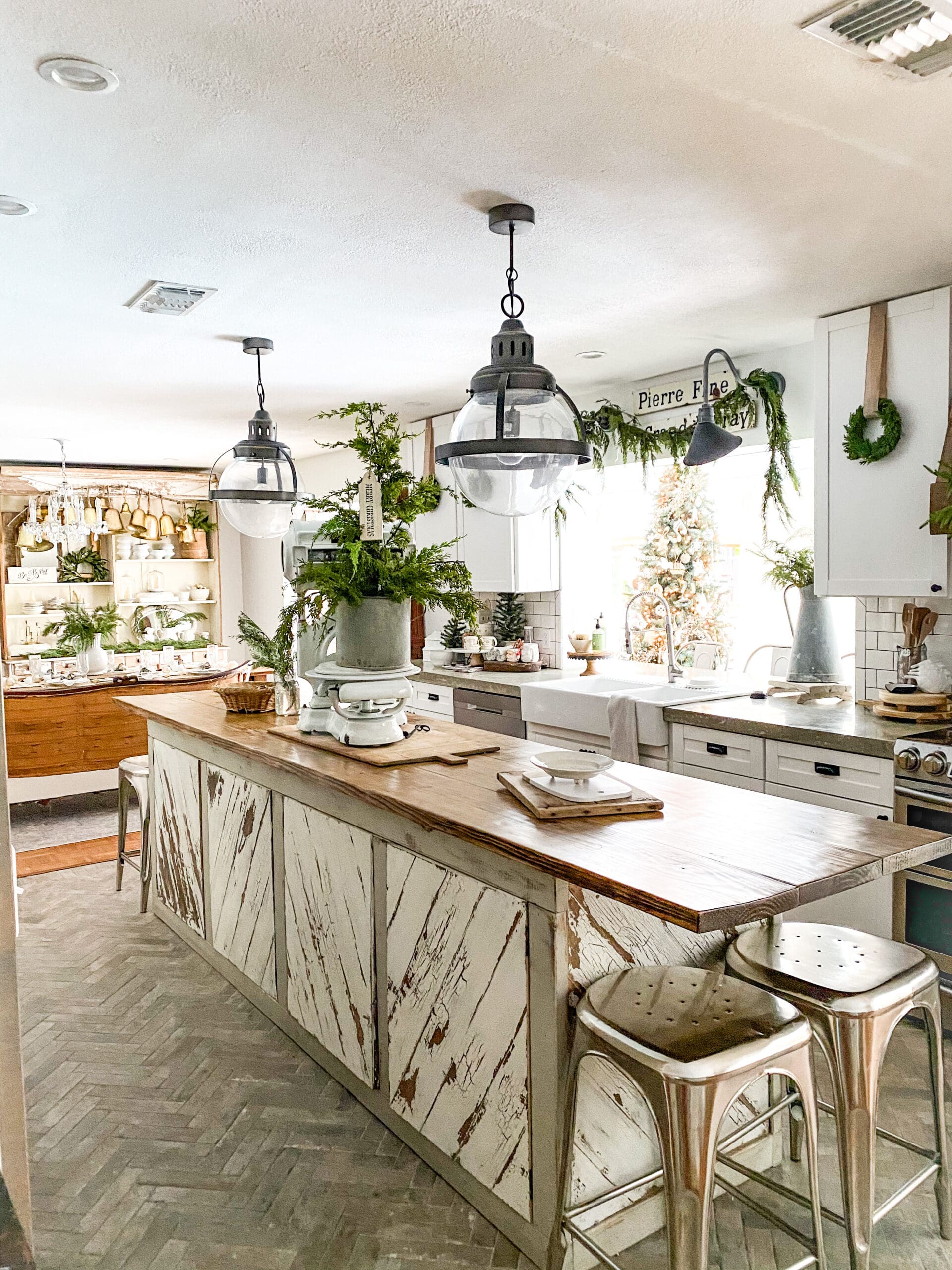 kitchen island styled with a vintage white scale with a small tree and garland strung between cabinets