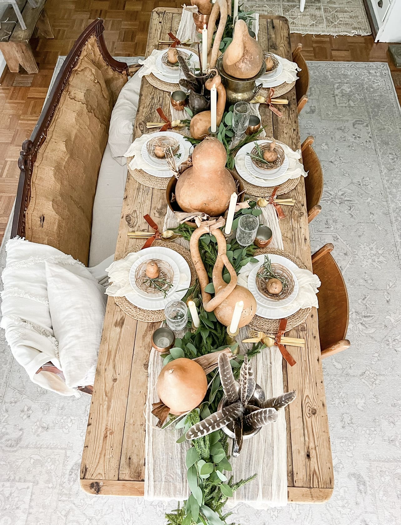 overhead view of a table scape featuring variously shaped gourds, feathers, and faux greenery