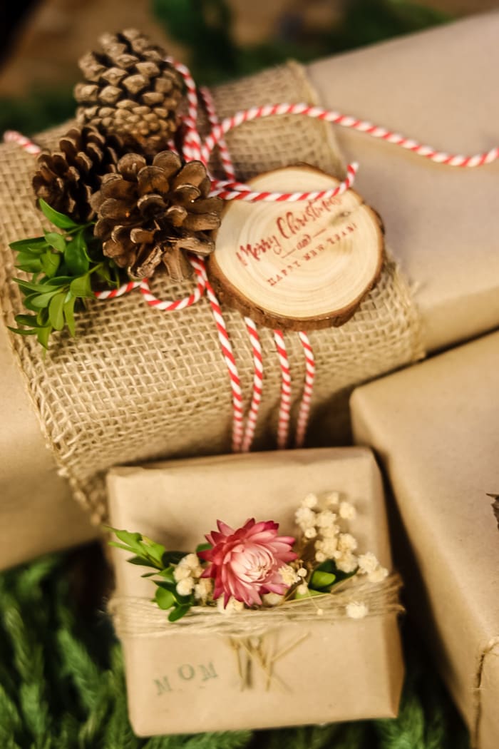 brown wrapping paper with burlap wrapped around it and pinecone and cranberry embellishments