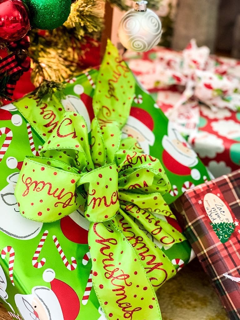 bright green wrapping paper with Santa hats and a bright green ribbon tied around the gift