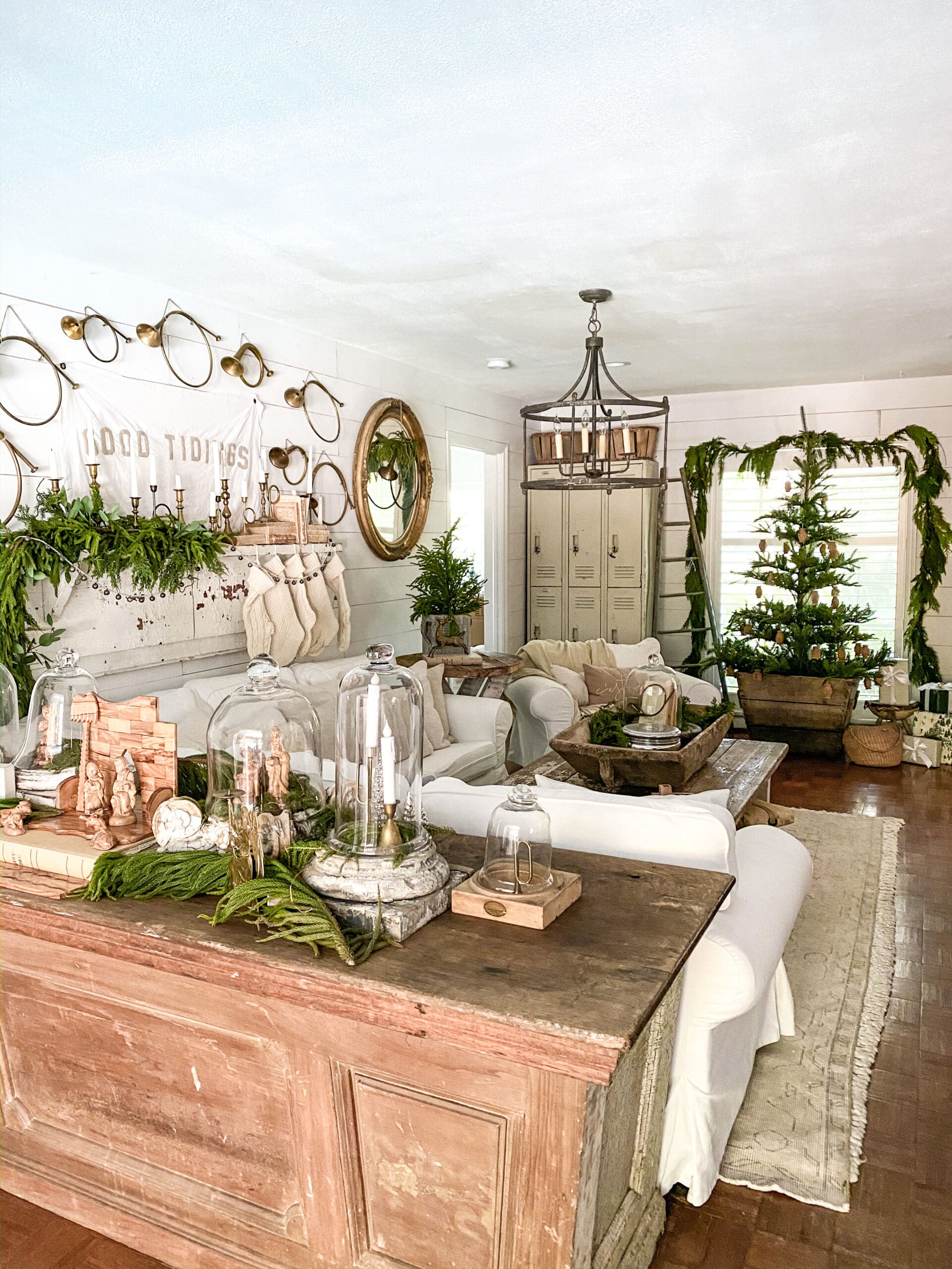 wide view of a Christmas family room styled with greenery and a French horn gallery wall and a Christmas tree