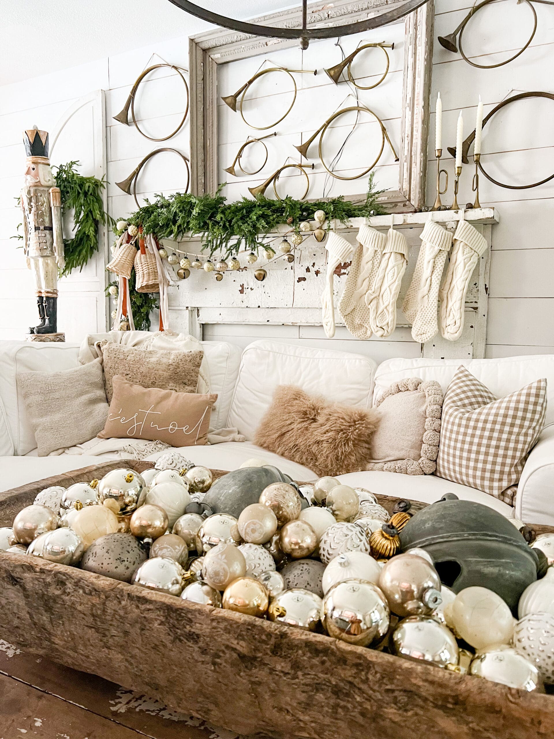 family room styled with a large dough bowl filled with mercury ornaments on a large white wooden coffee table