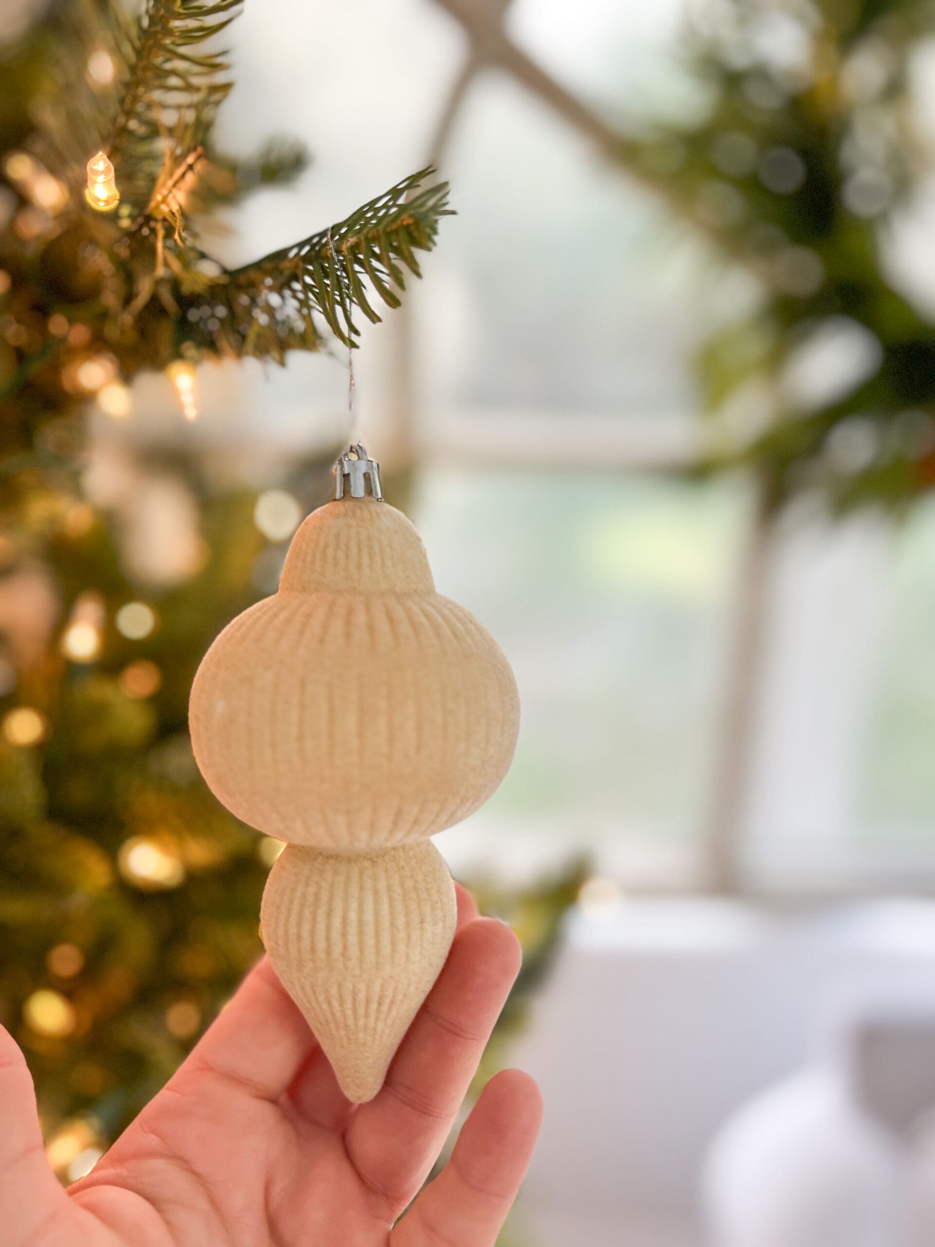 a flocked ornament hung from a sparse Christmas tree
