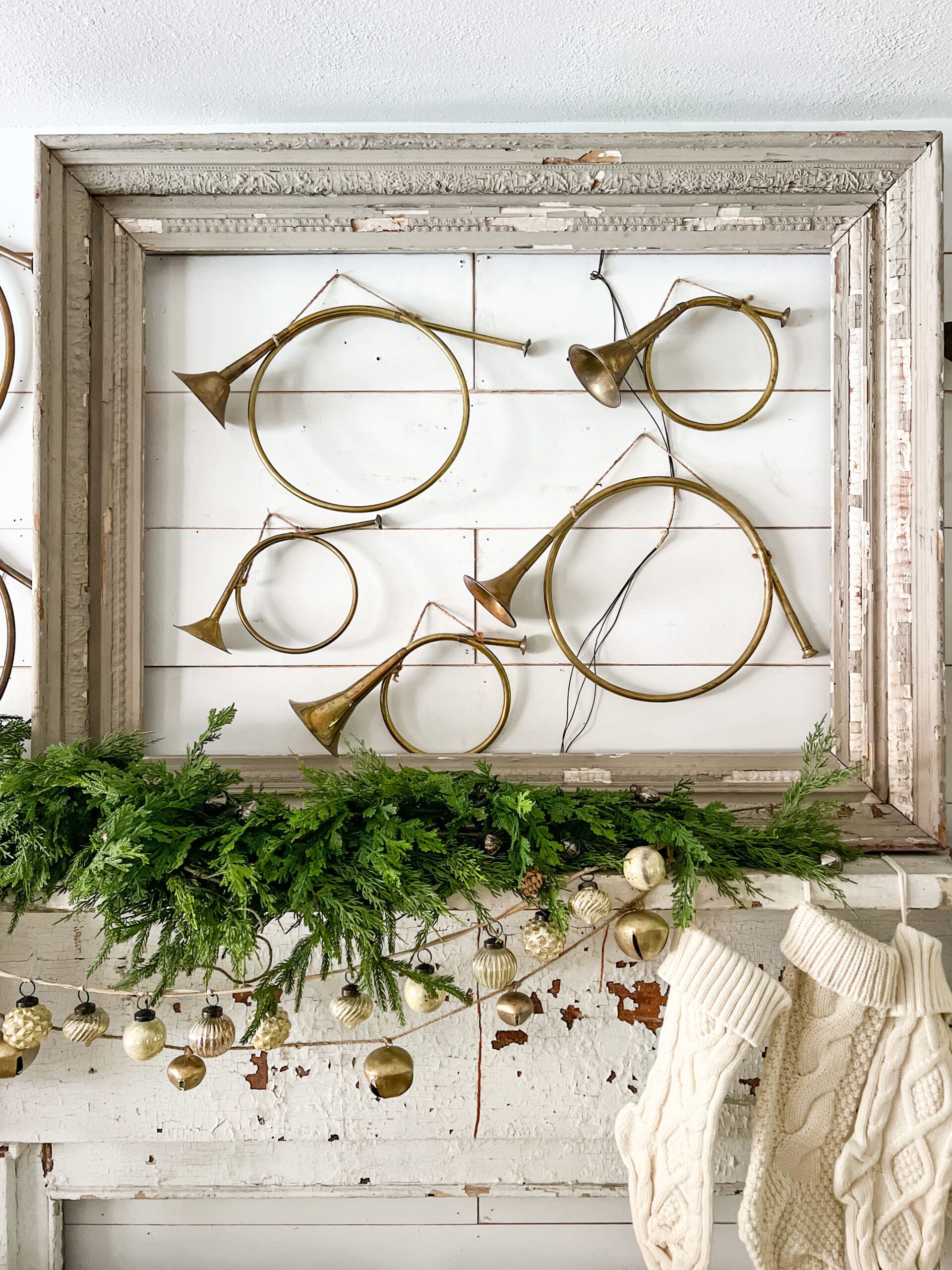 smaller French horns hung on a wall inside of a large gray frame