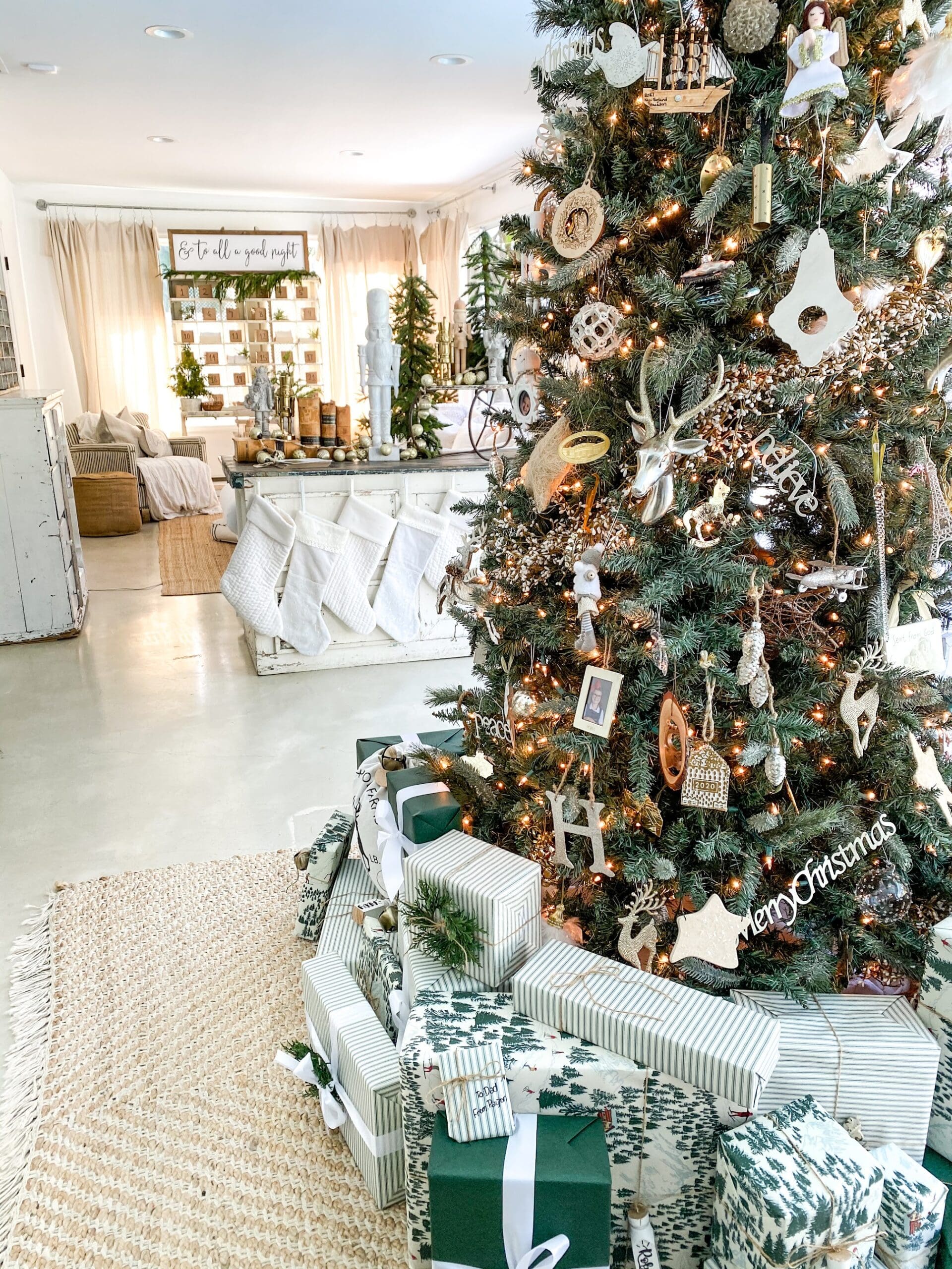 White and green colored wrapped presents underneath a large Christmas tree