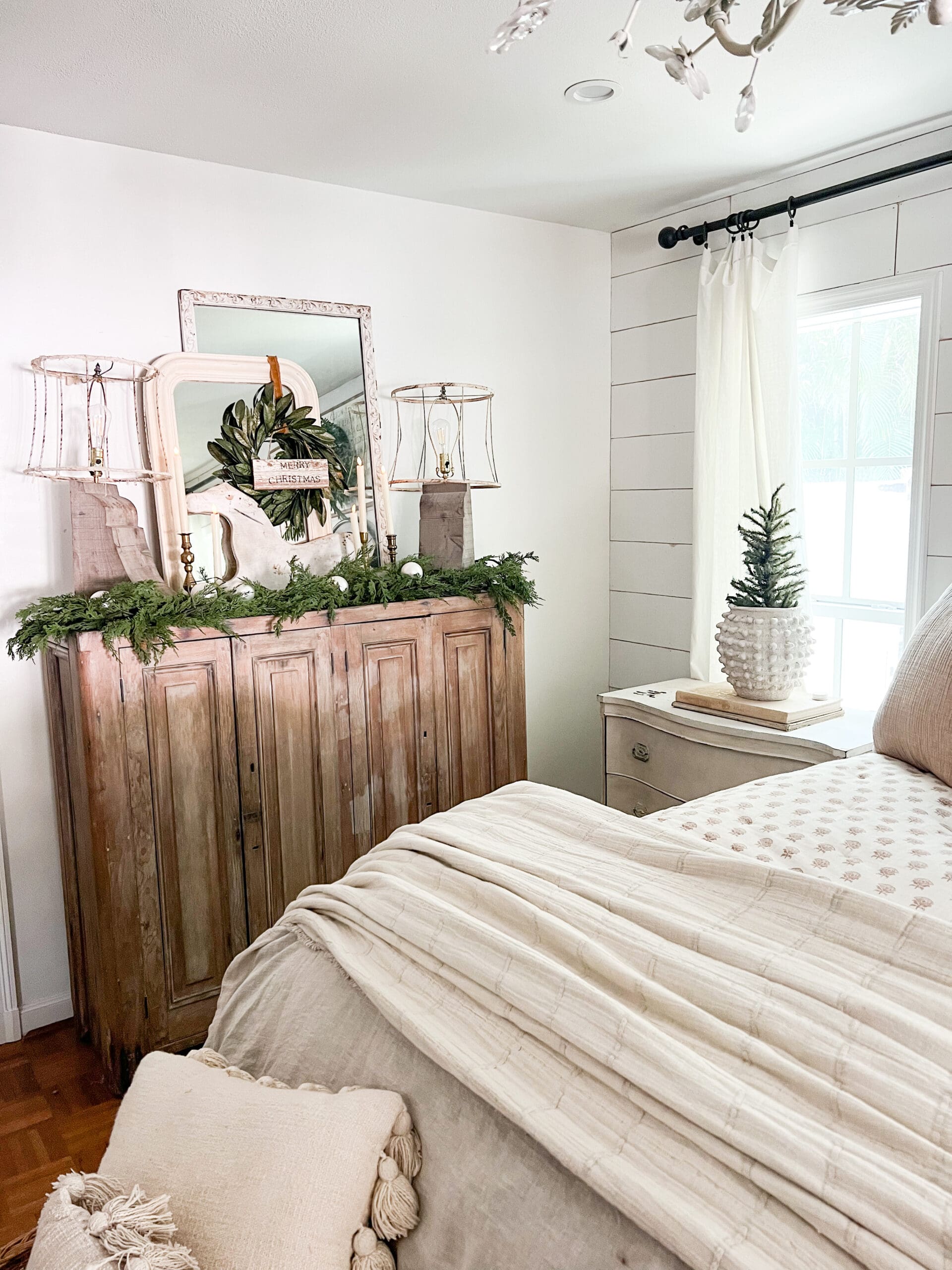 wooden nightstand styled for Christmas with holiday greenery and a small tree