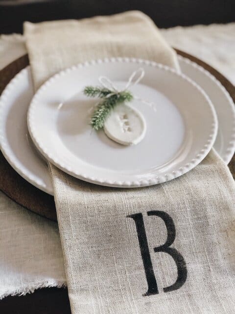 DIY table place setting with a small button and greenery at each place
