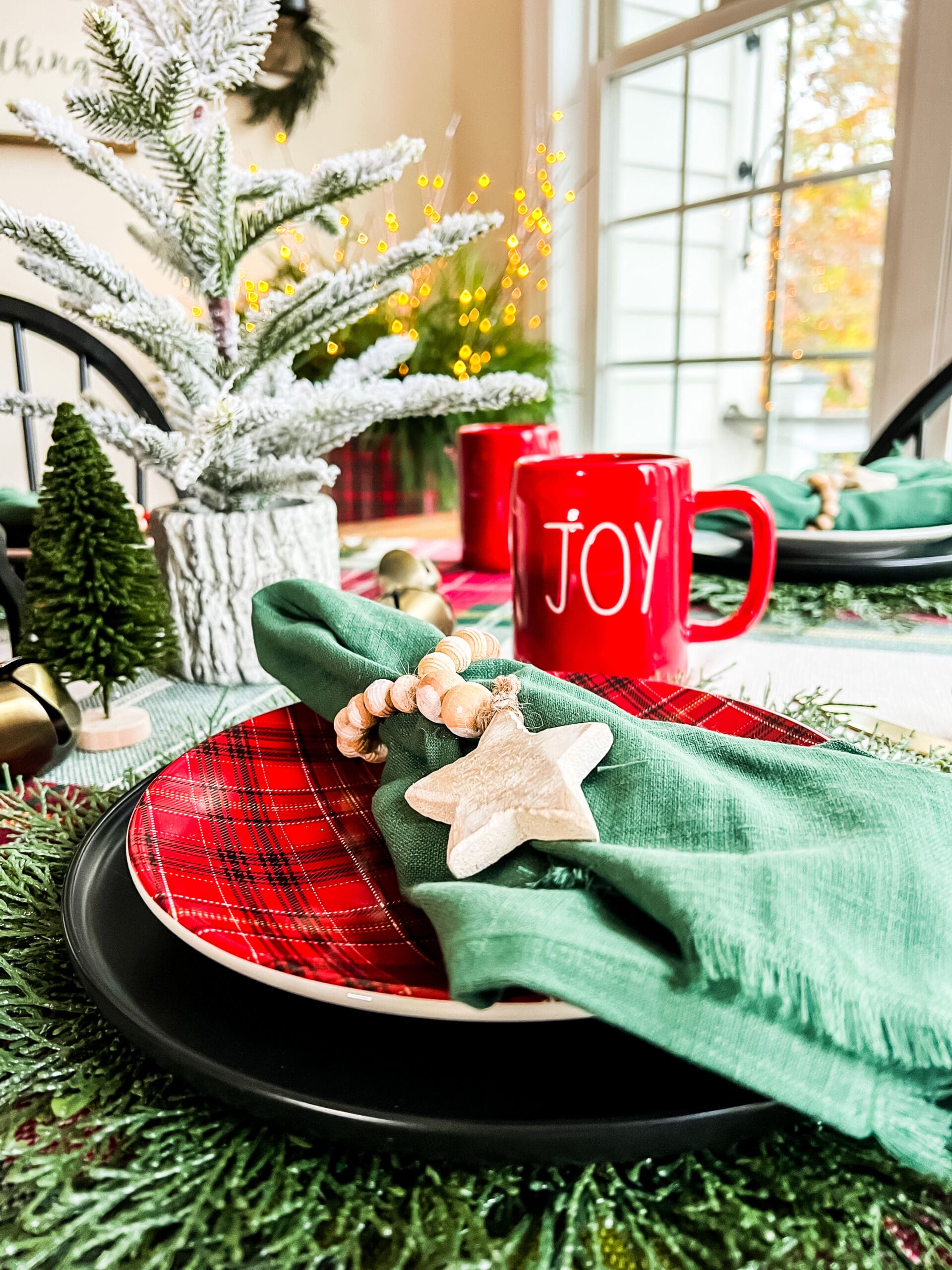 table setting with plaid plates and green napkins as well as Christmas cups