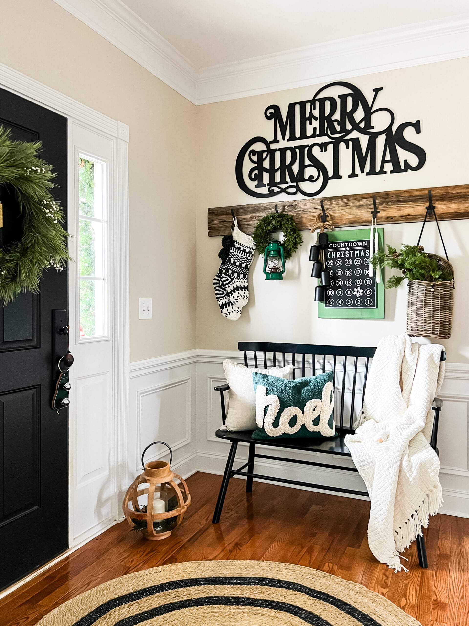 small black bench with Christmas pillows and a black Merry Christmas sign hung on the wall behind