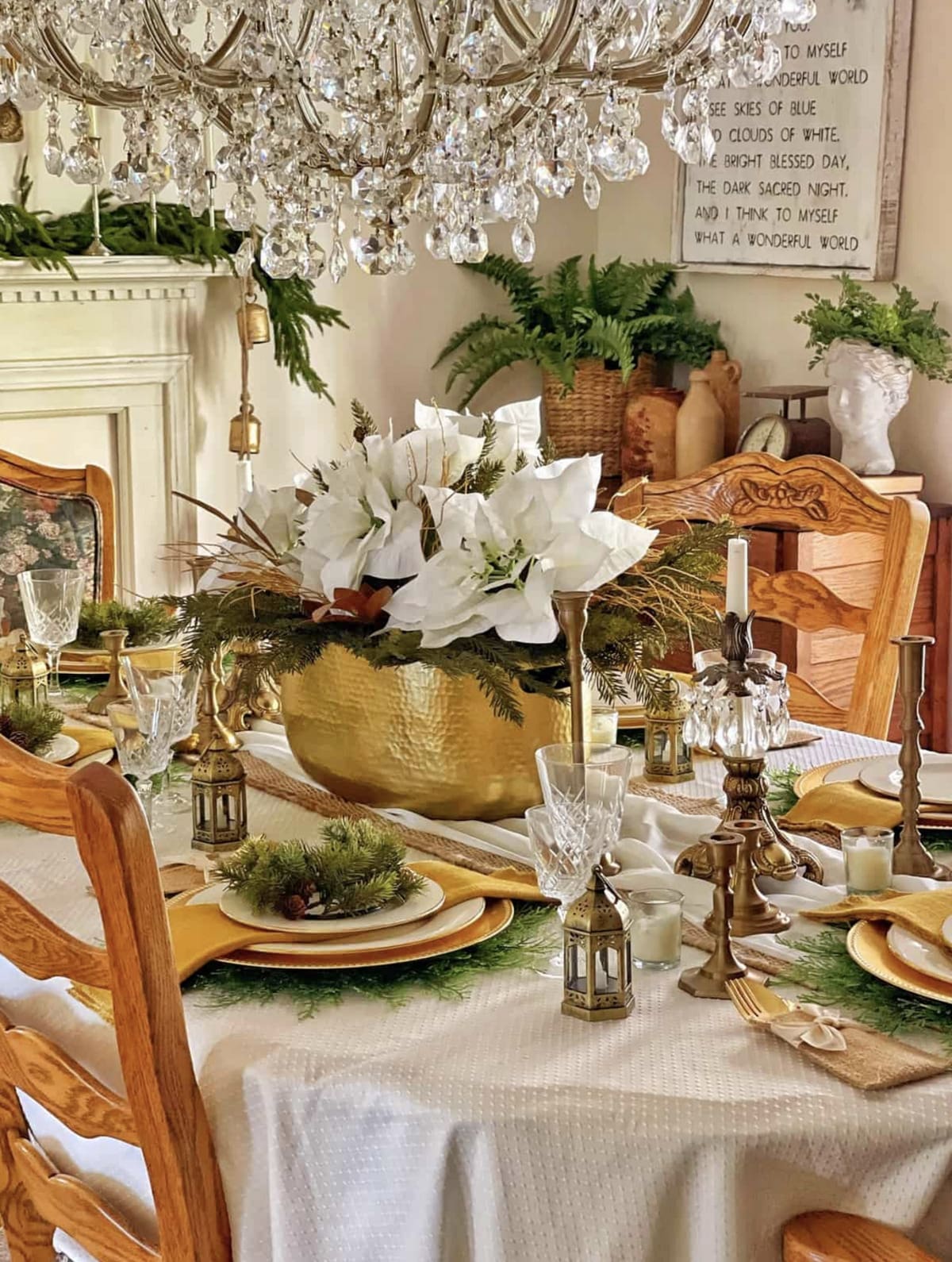 christmas table scape with an arrangement of Christmas greenery and flowers in a vintage gold vessel as a centerpiece