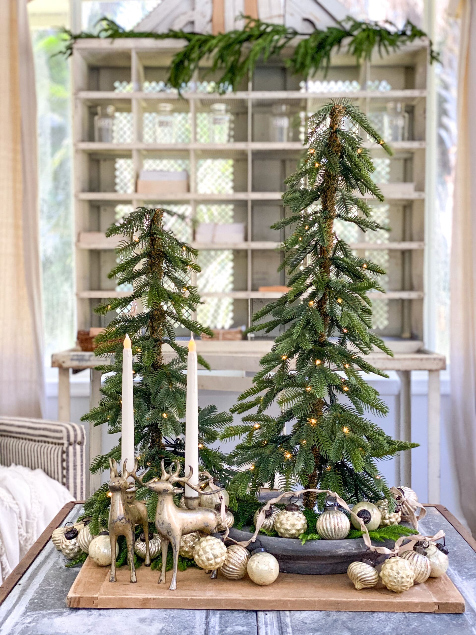 coffee table vignette styled with Christmas trees and gold ornaments and brass deer candlesticks