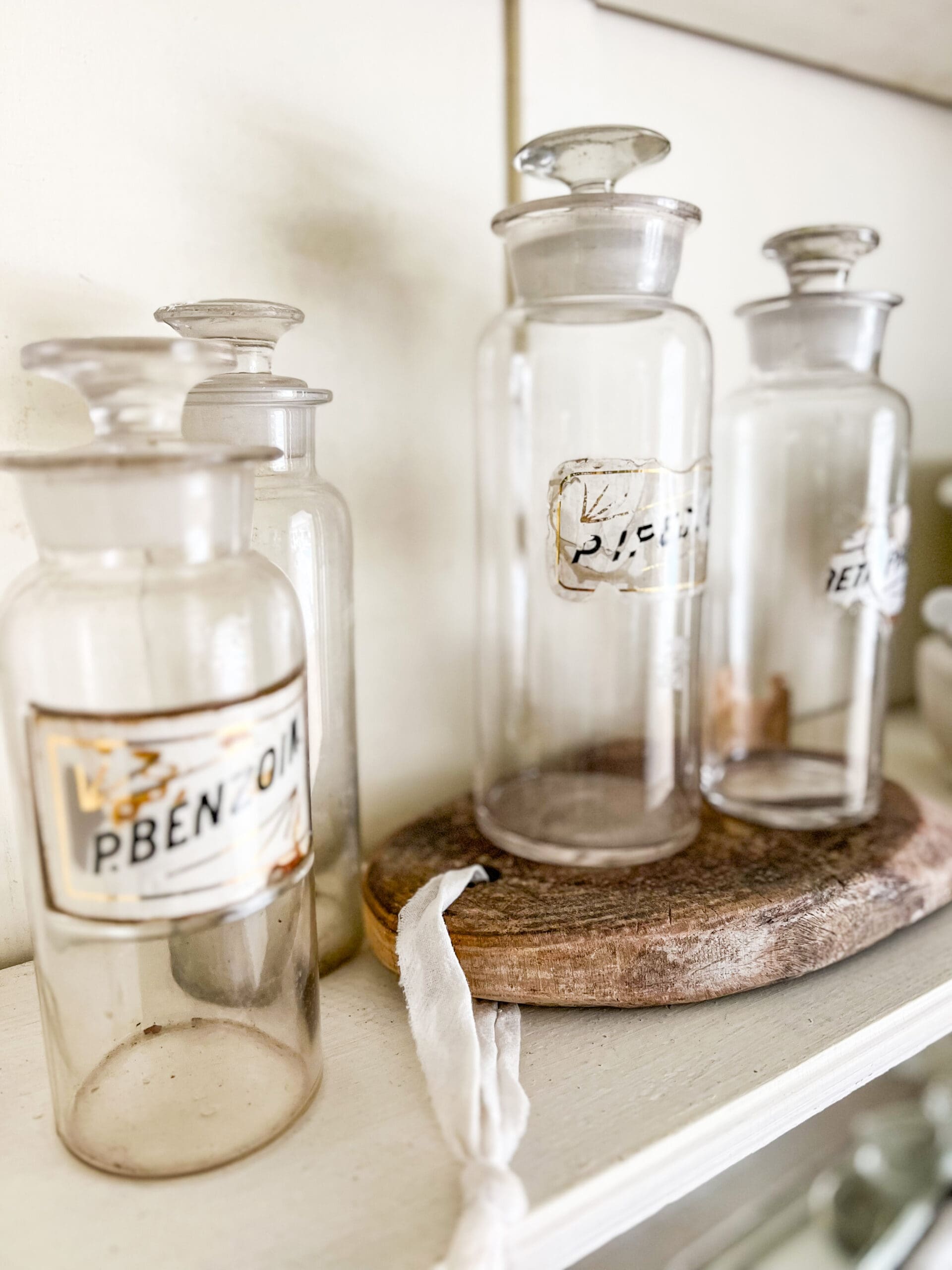 variously labeled vintage pharmaceutical glass bottles styled on an apothecary shelf
