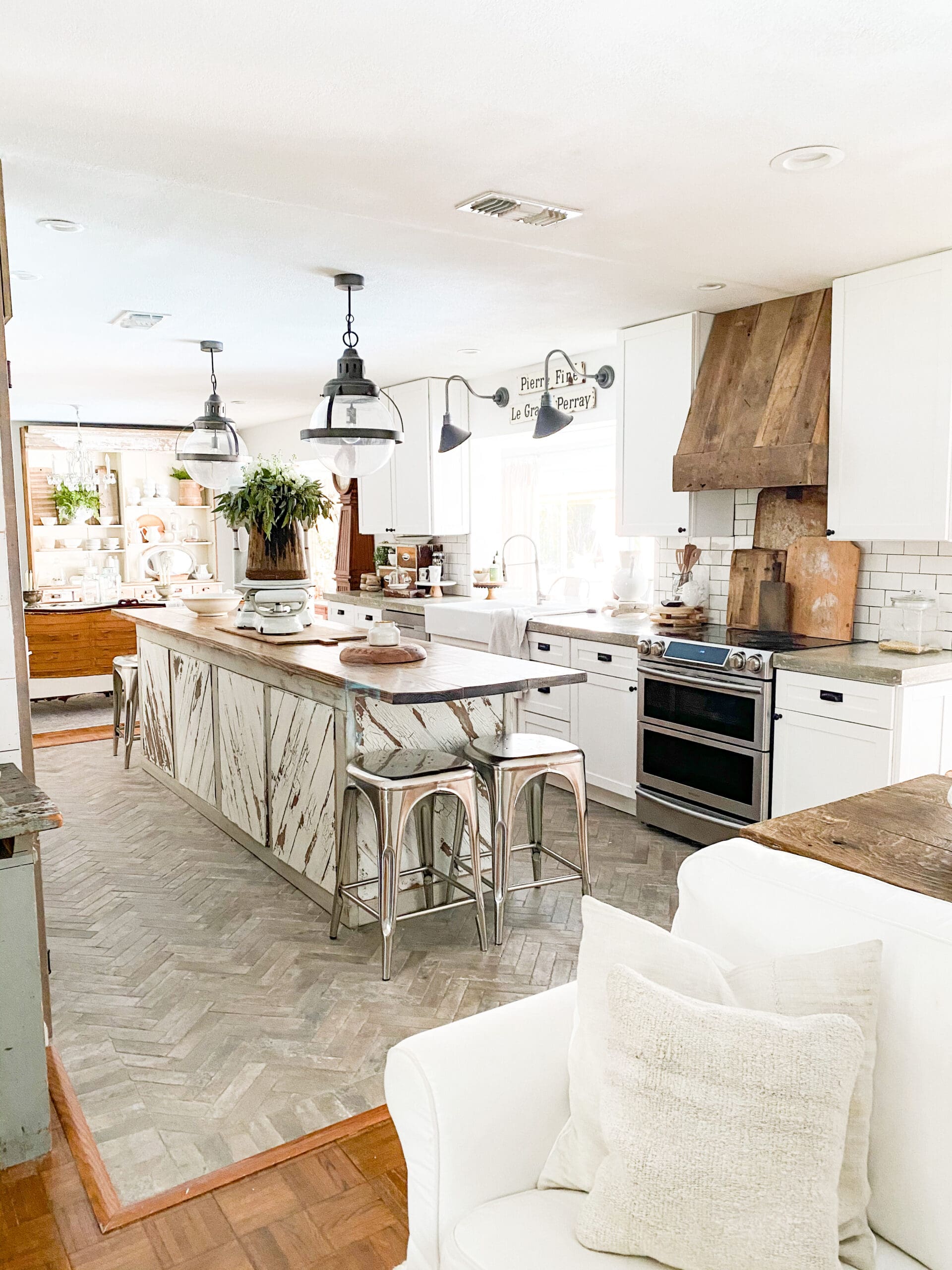 wide view of a beautiful neutral kitchen with a large wood island and concrete countertops with white cabinets