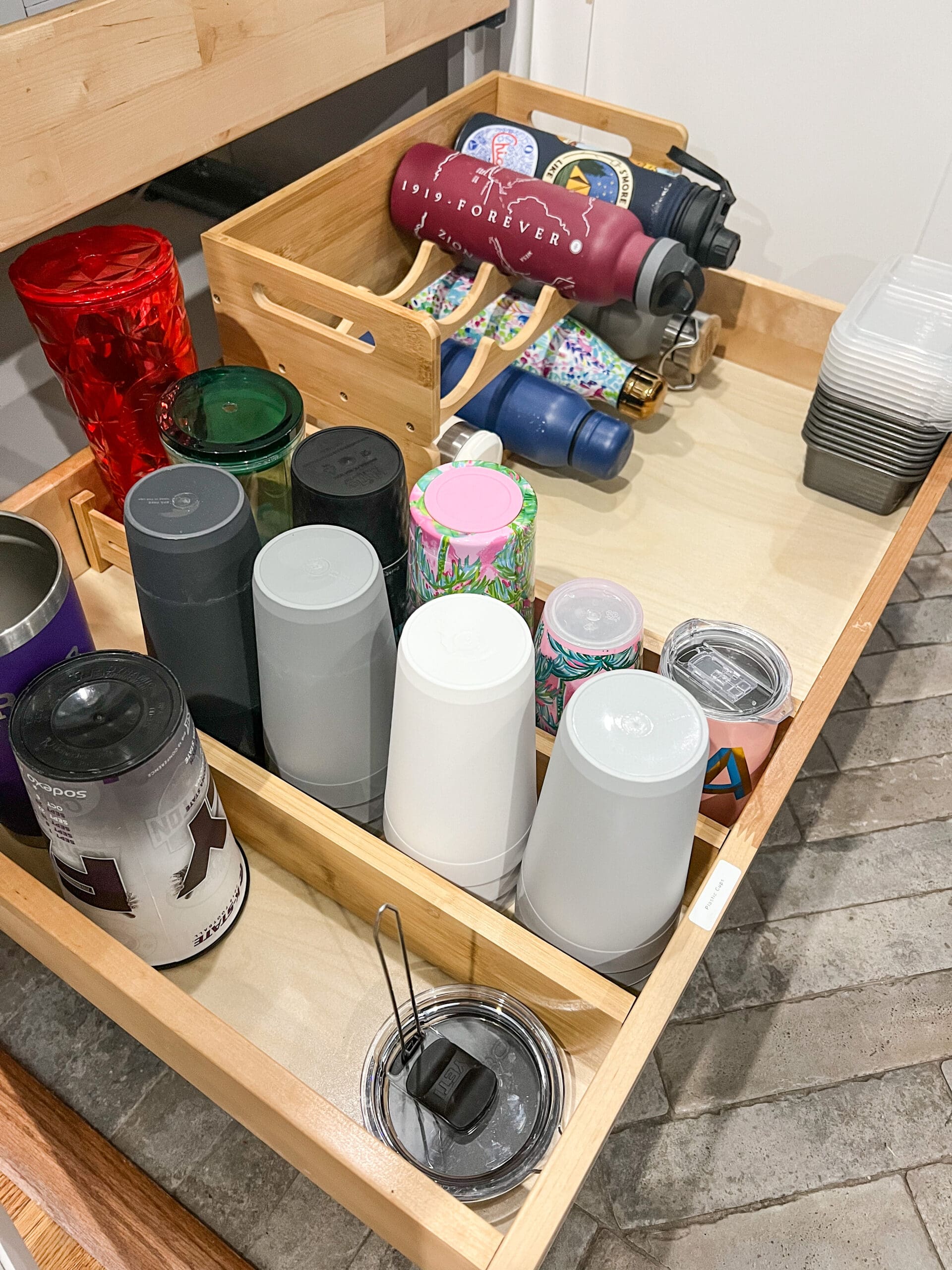 a wooden drawer pulled out to show various types of water bottles in different organizers